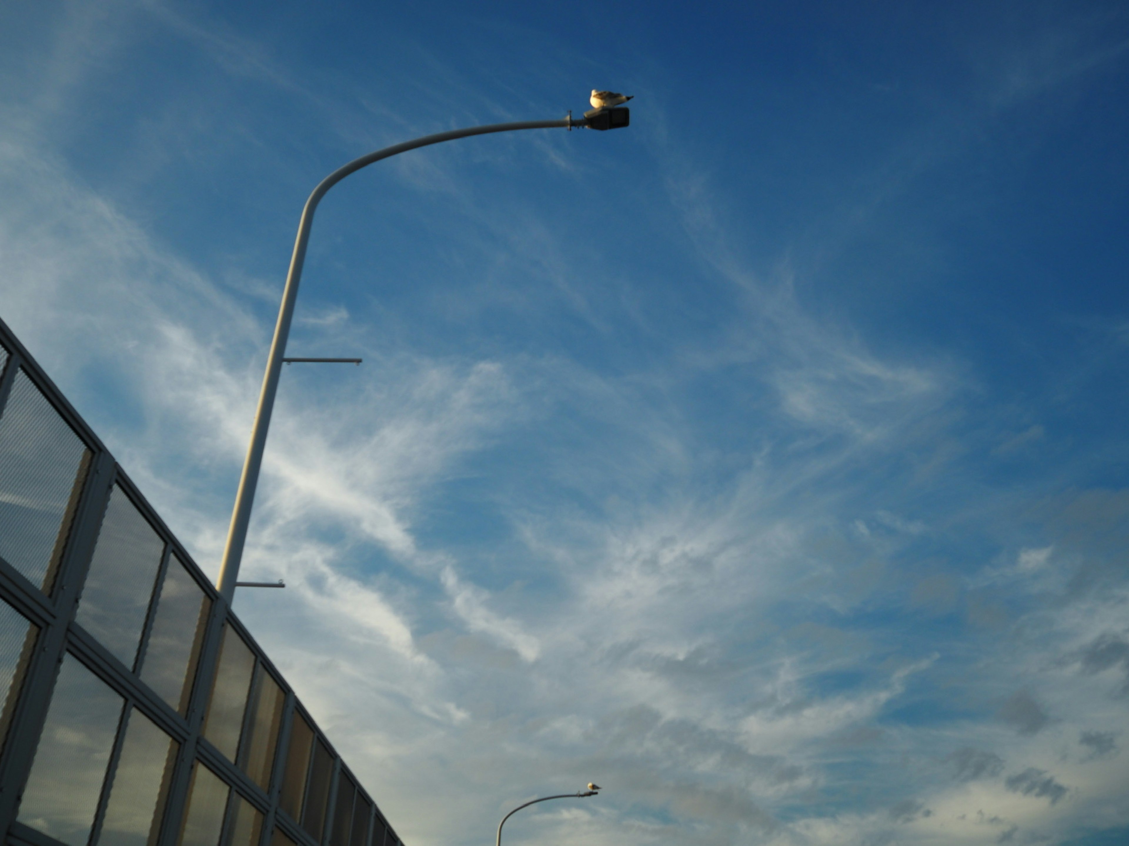 Farola contra un cielo azul con nubes delgadas