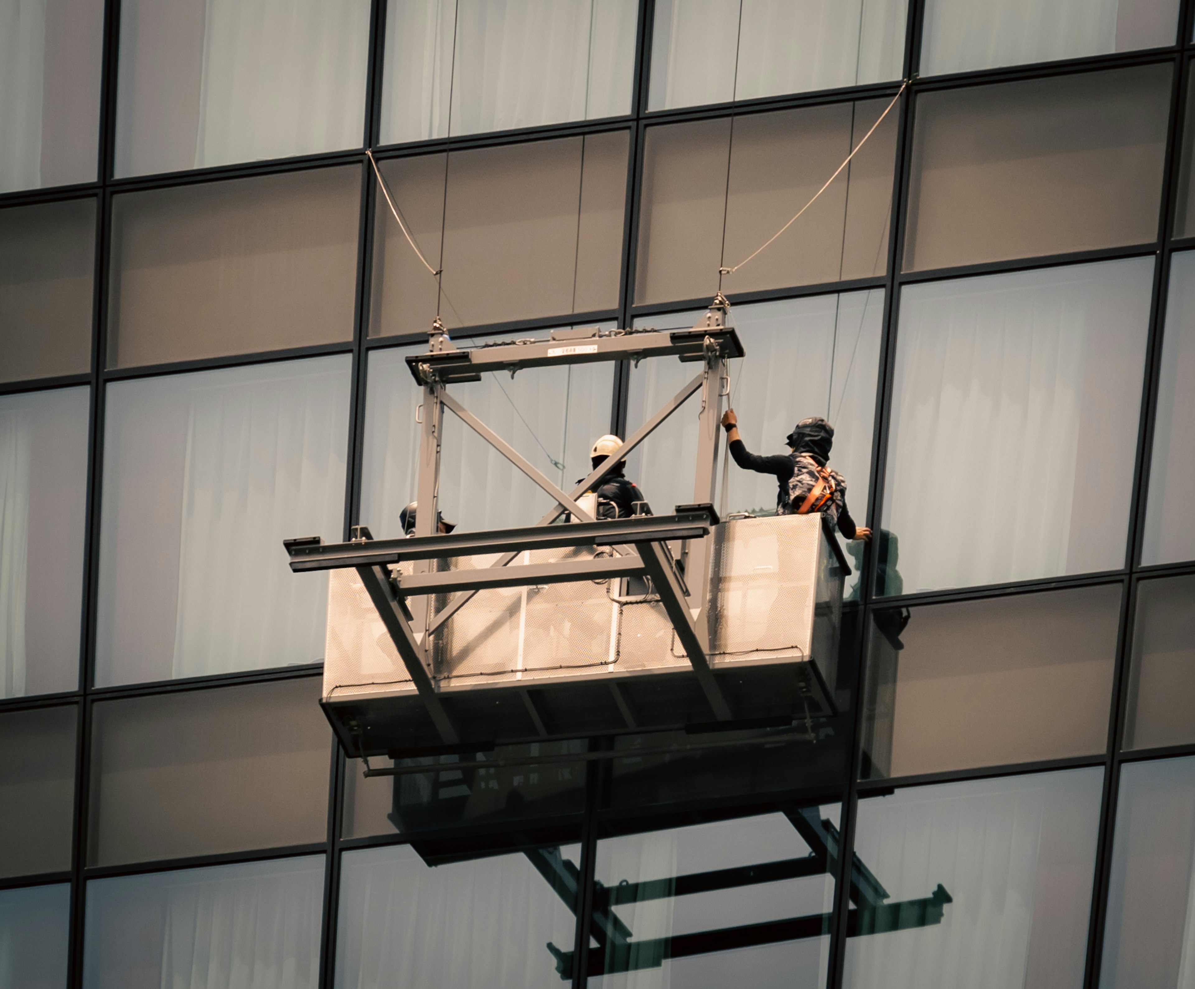 Workers cleaning windows on a high-rise building from a suspended platform