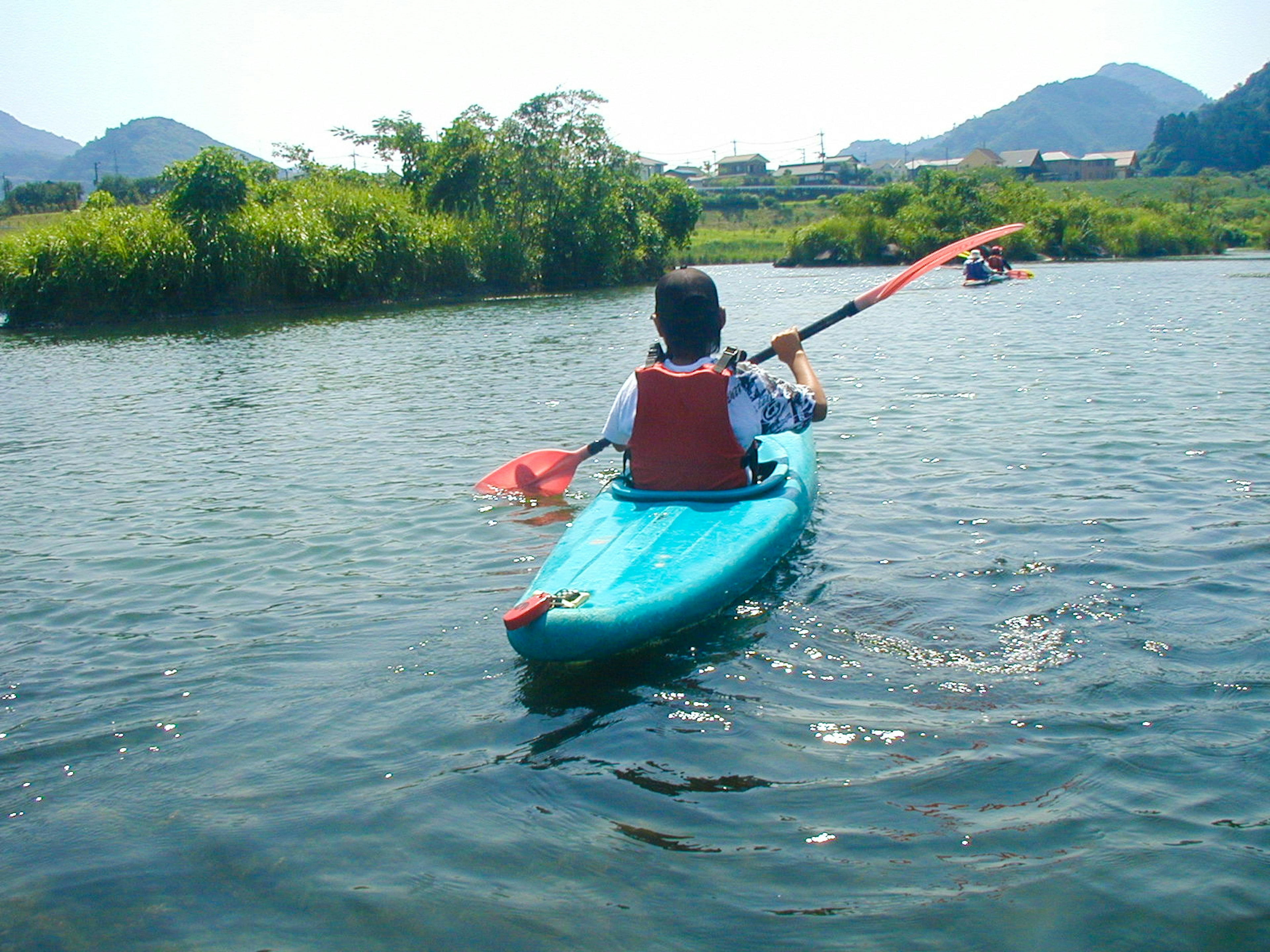 Personne pagayant dans un kayak bleu sur une rivière calme