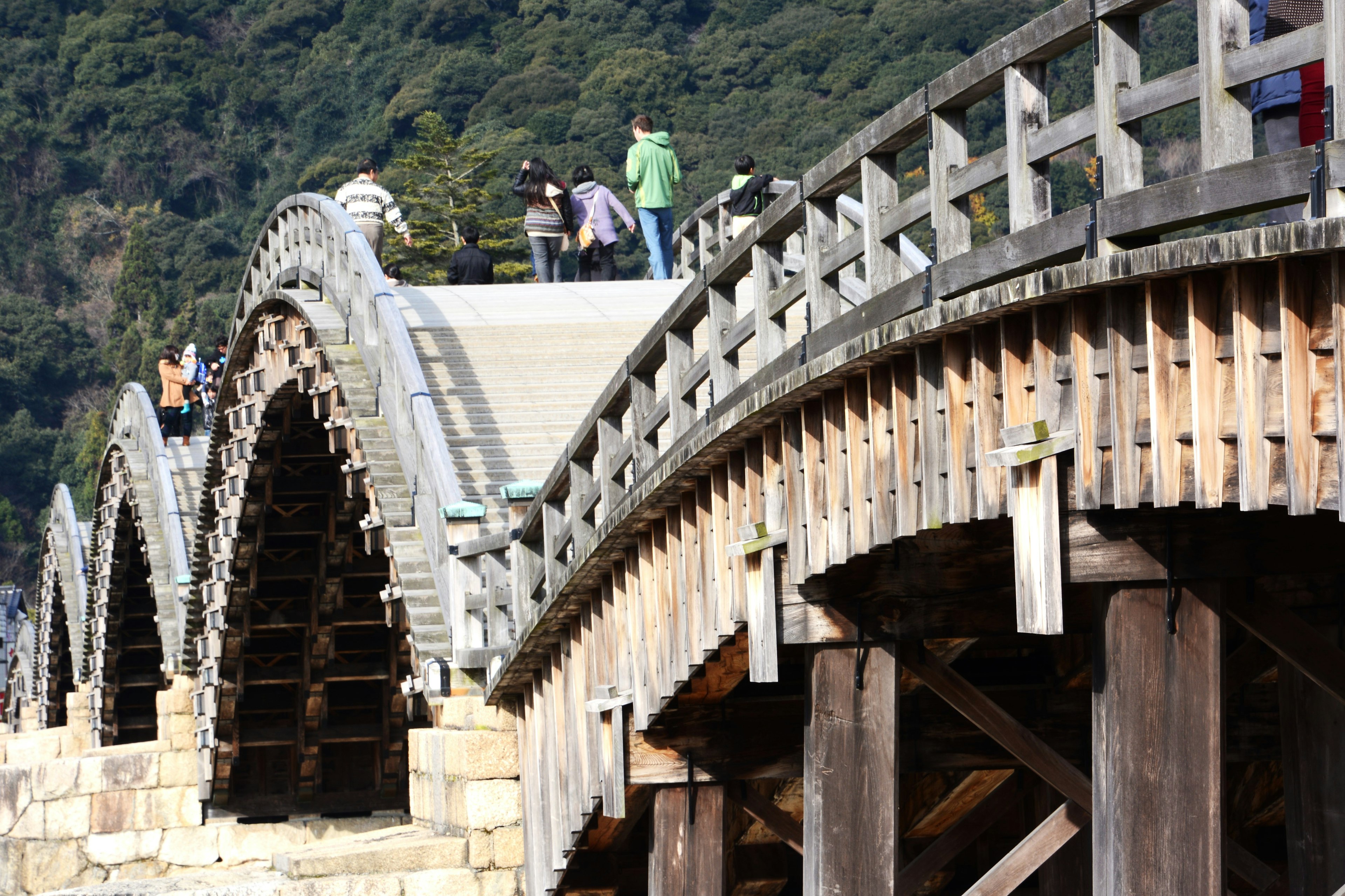 Detailed view of a wooden arch bridge with visitors