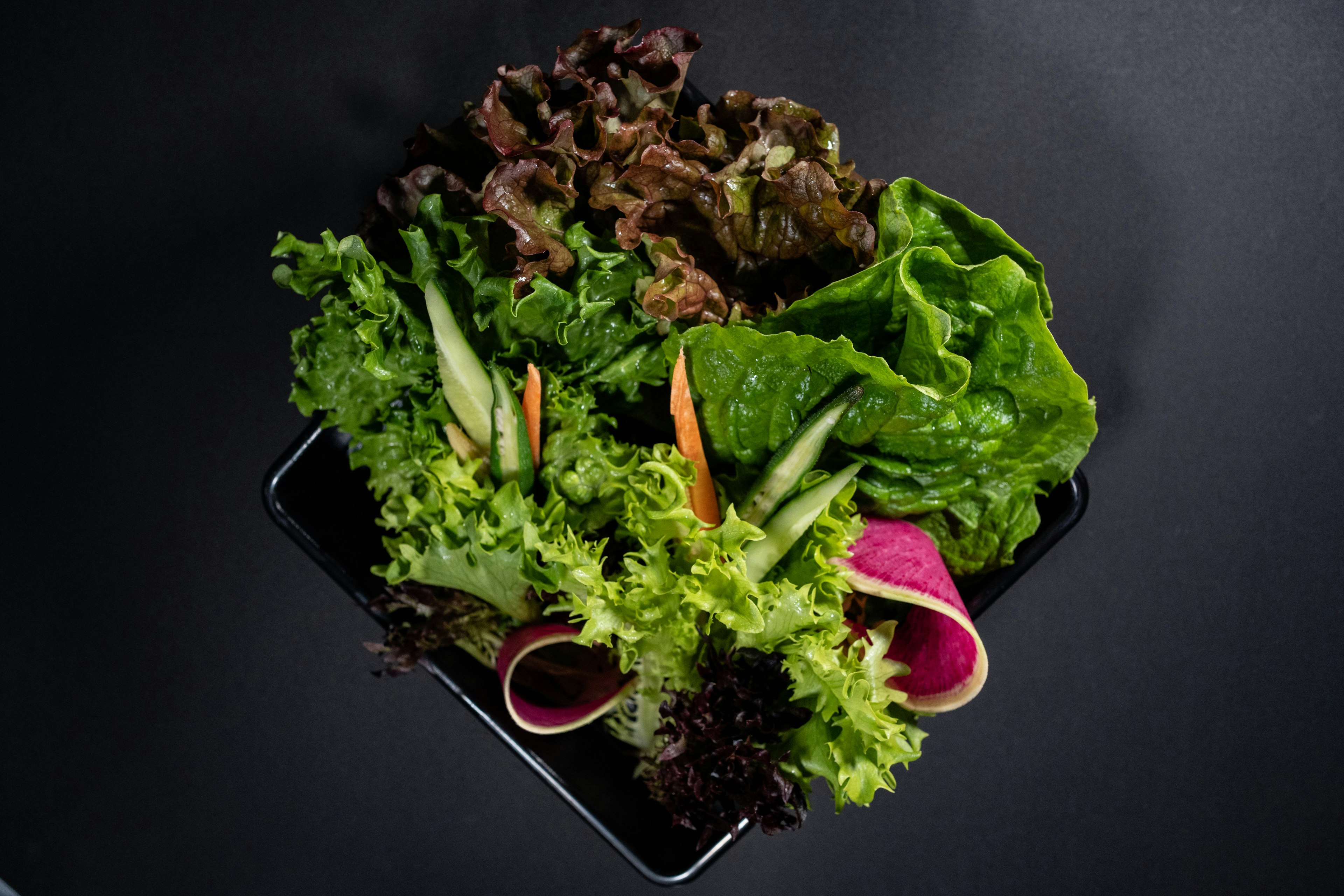 Fresh assorted lettuce and vegetables on a black background