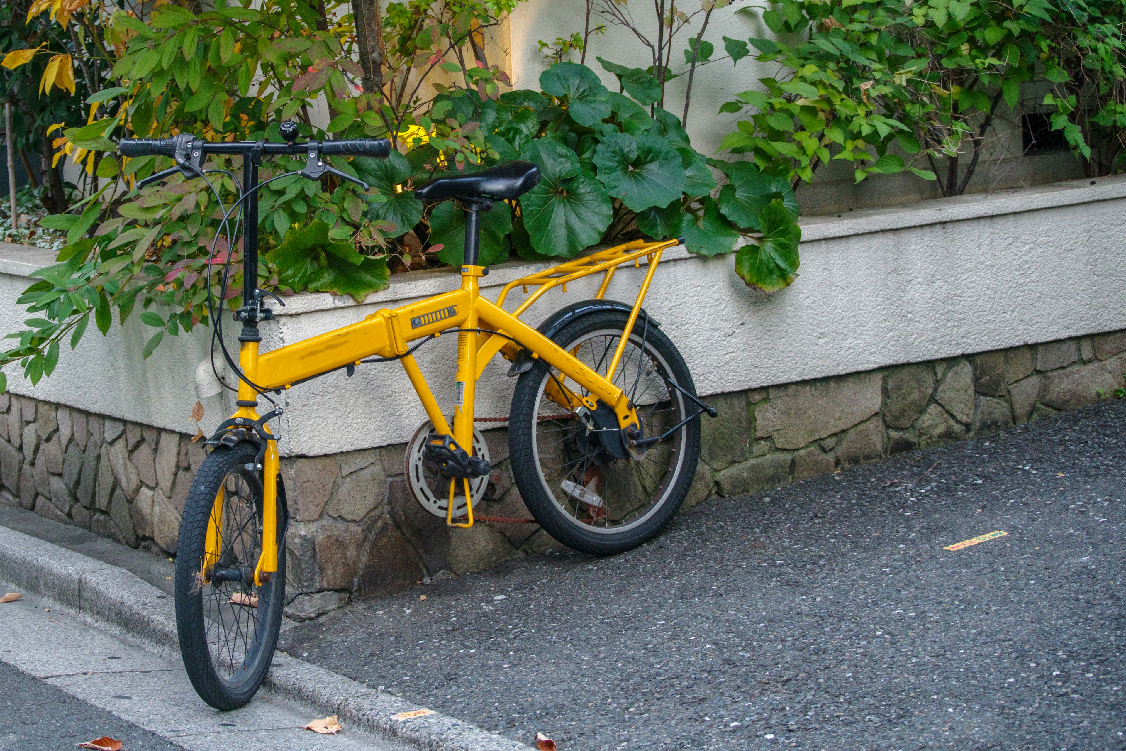 黄色の折りたたみ自転車が壁に寄りかかっている風景