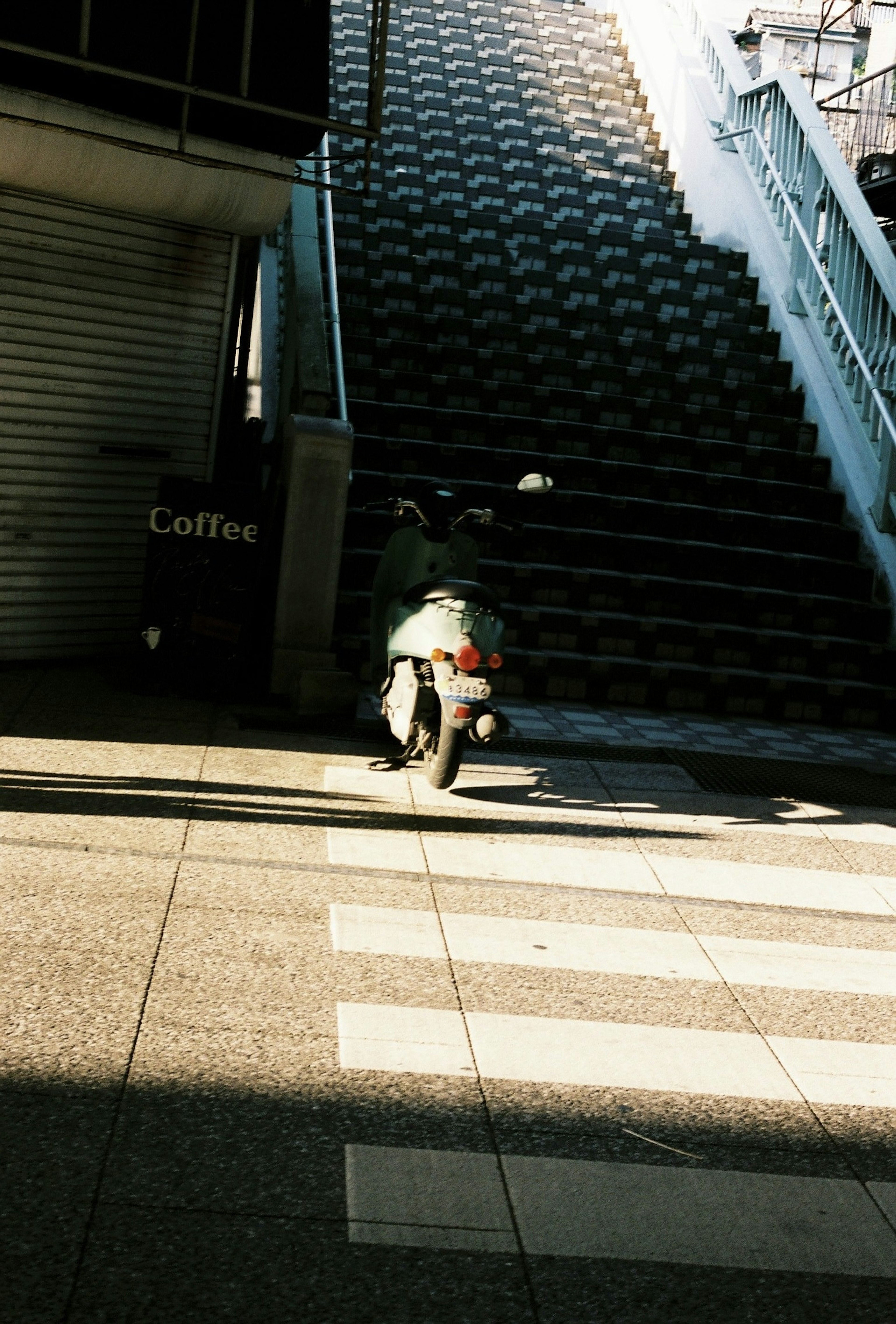 階段の前に停まっているバイクと影のコントラスト