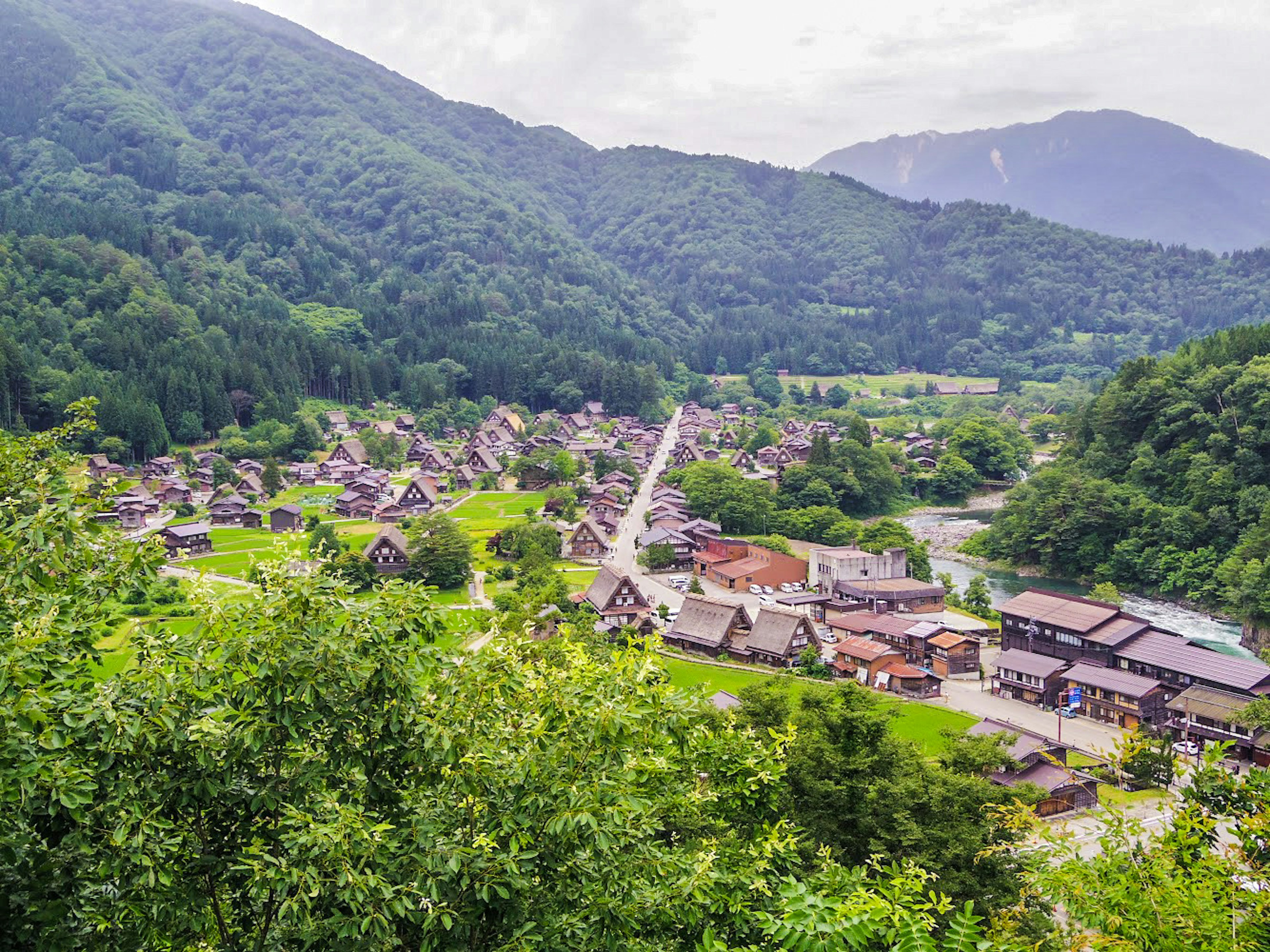 Malersicher Blick auf ein Dorf umgeben von Bergen üppigen grünen Feldern und traditionellen Häusern