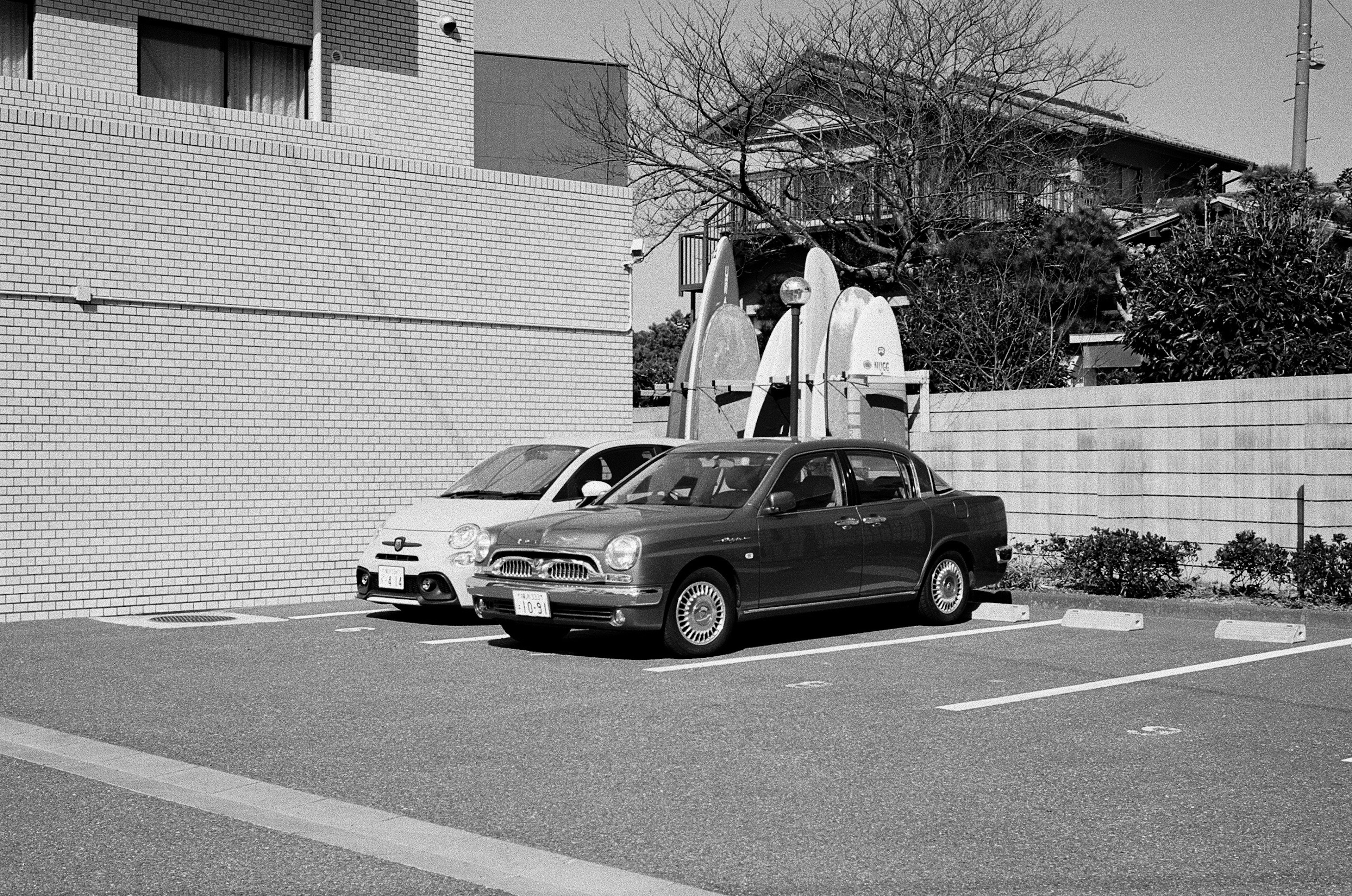 白黒の駐車場に停まっている二台の車とその背景の建物