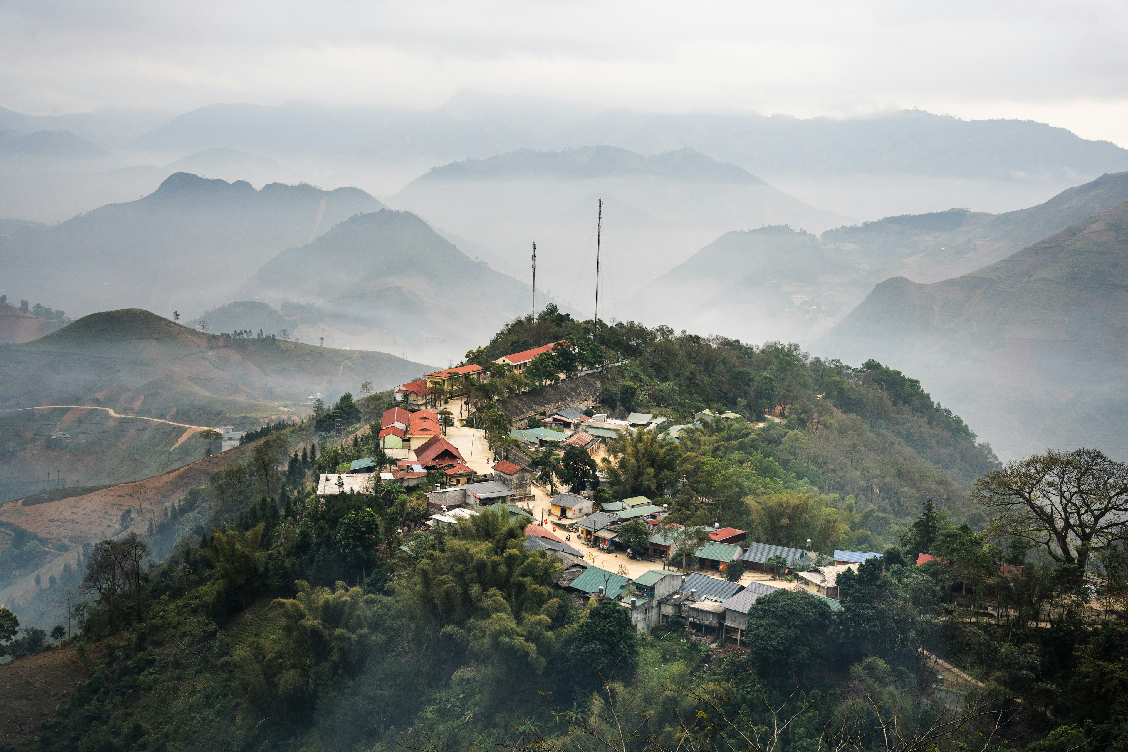 A small village on a mountain top surrounded by mist and mountains