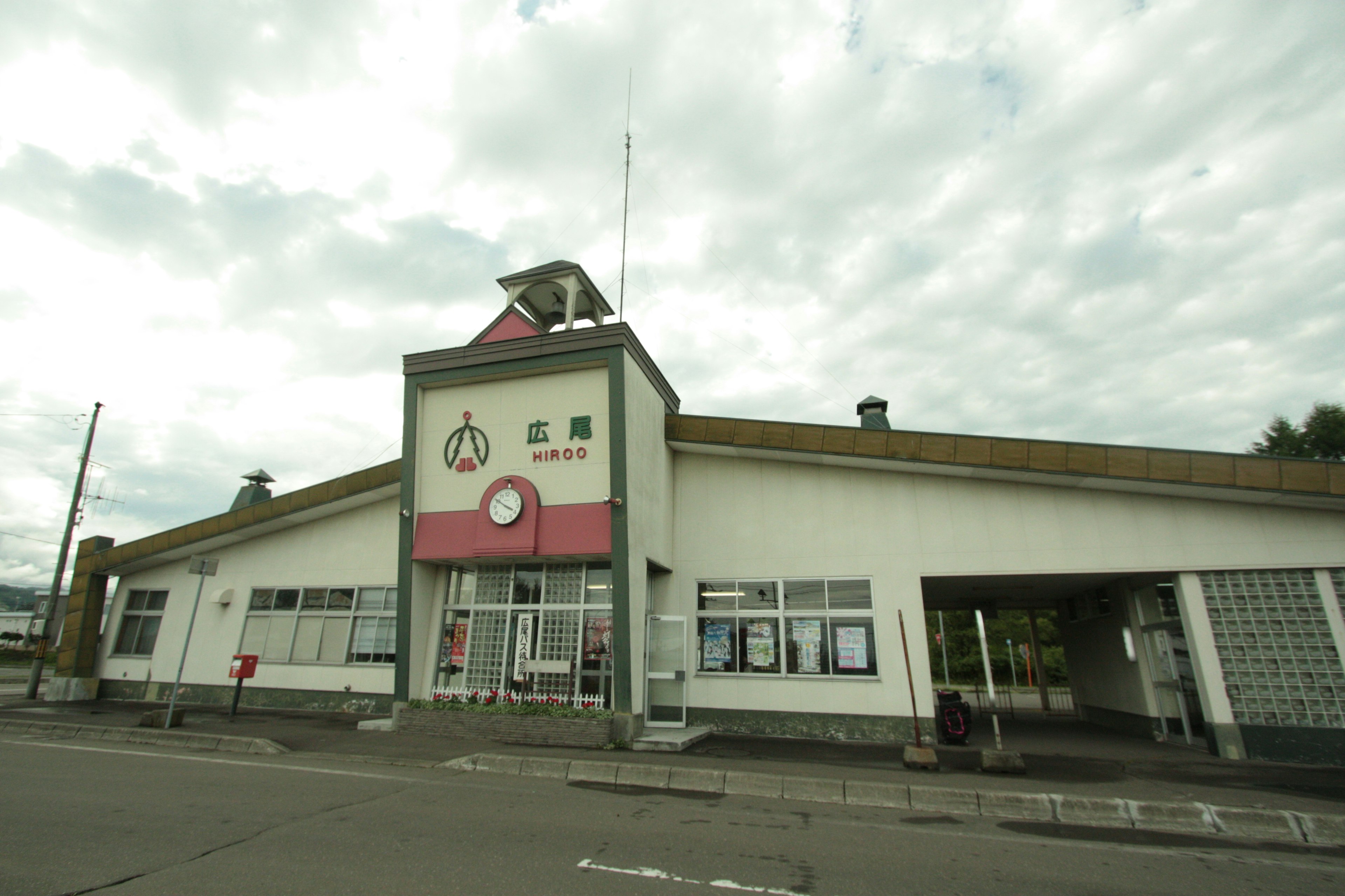 Exterior view of a building with a red roof under a cloudy sky featuring several windows