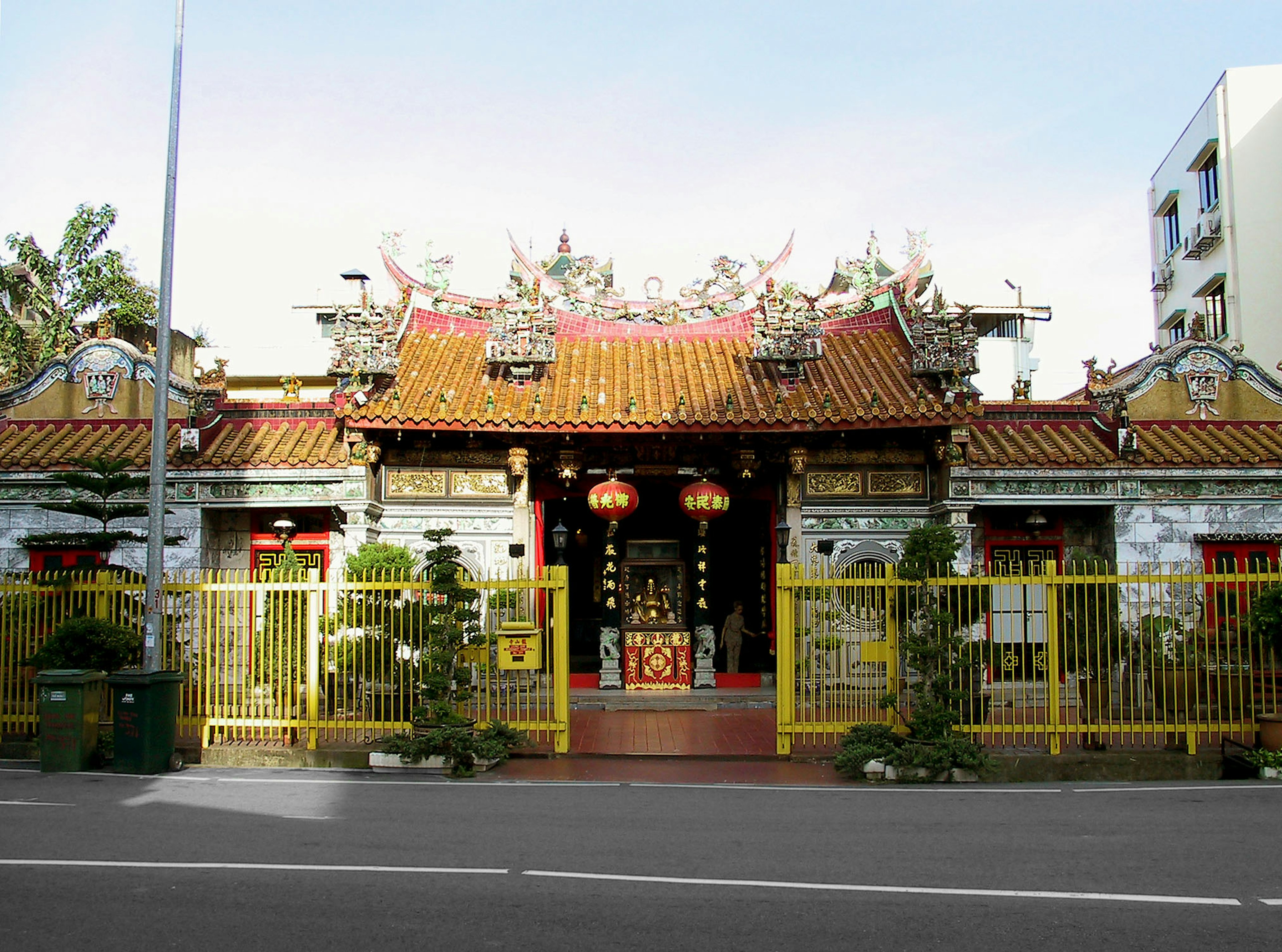 Extérieur d'un temple traditionnel avec des décorations colorées entouré d'une clôture jaune