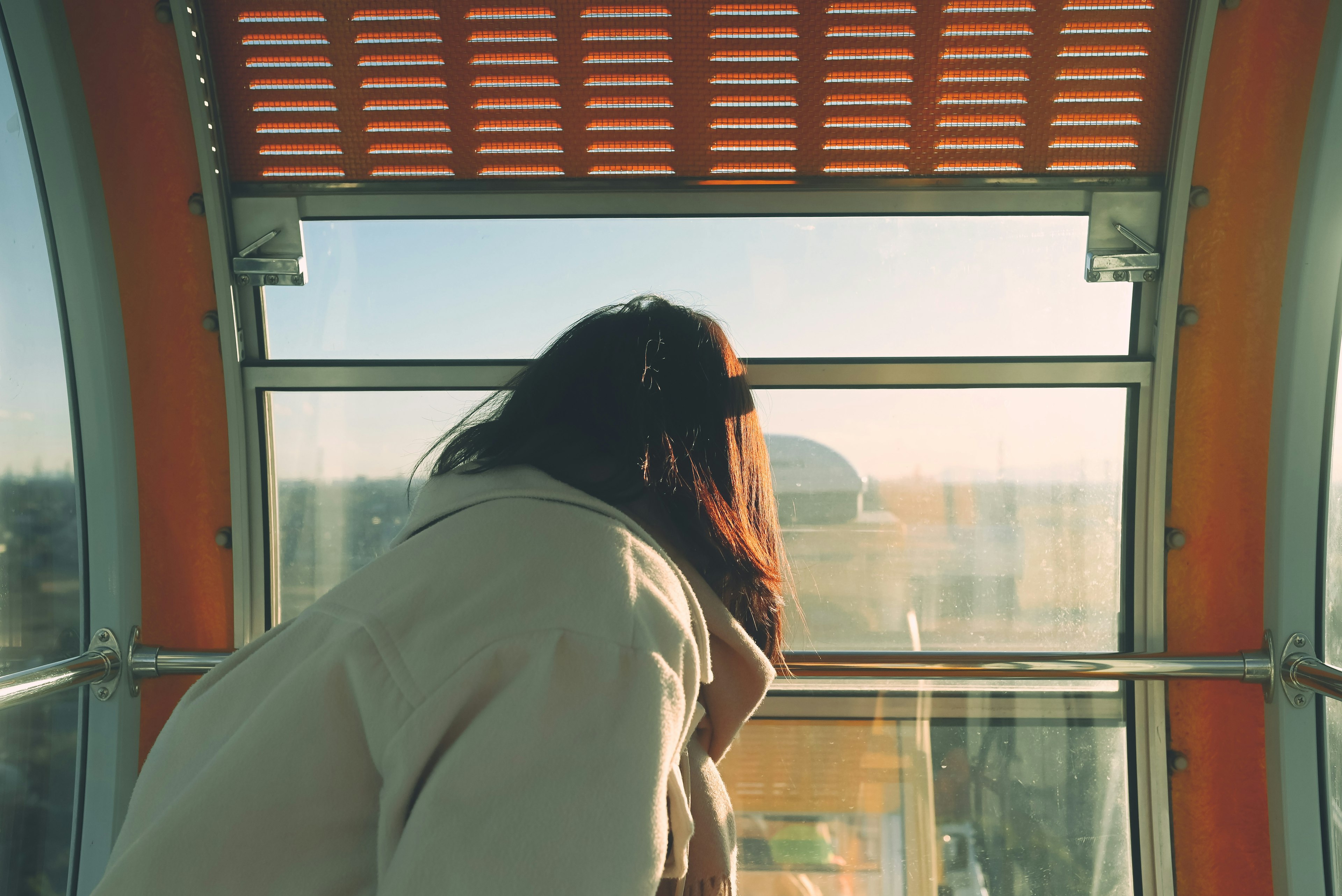 Une femme regardant par la fenêtre avec la lumière du soleil qui entre