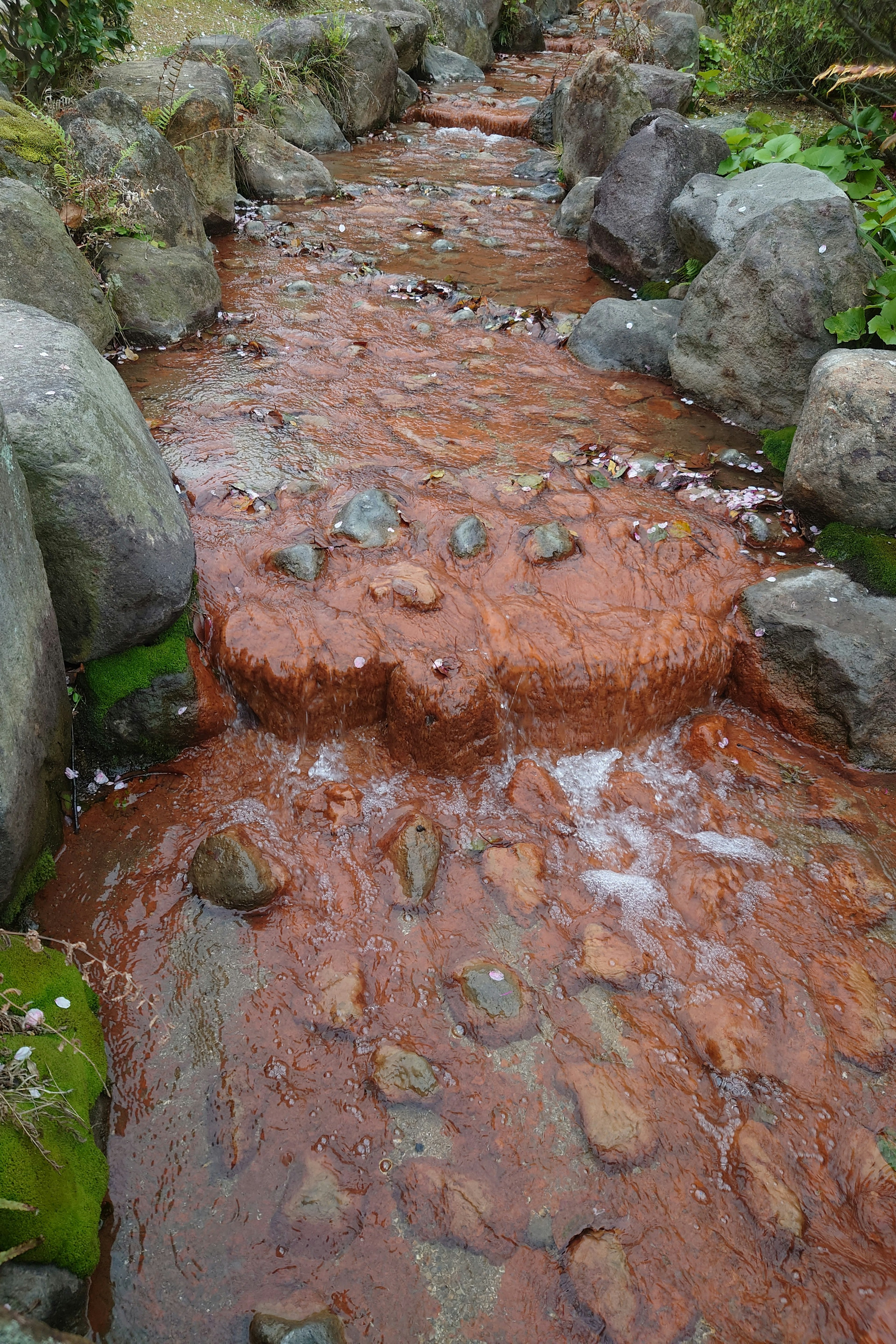 Ein Bach mit rotem Wasser, der über Steine fließt