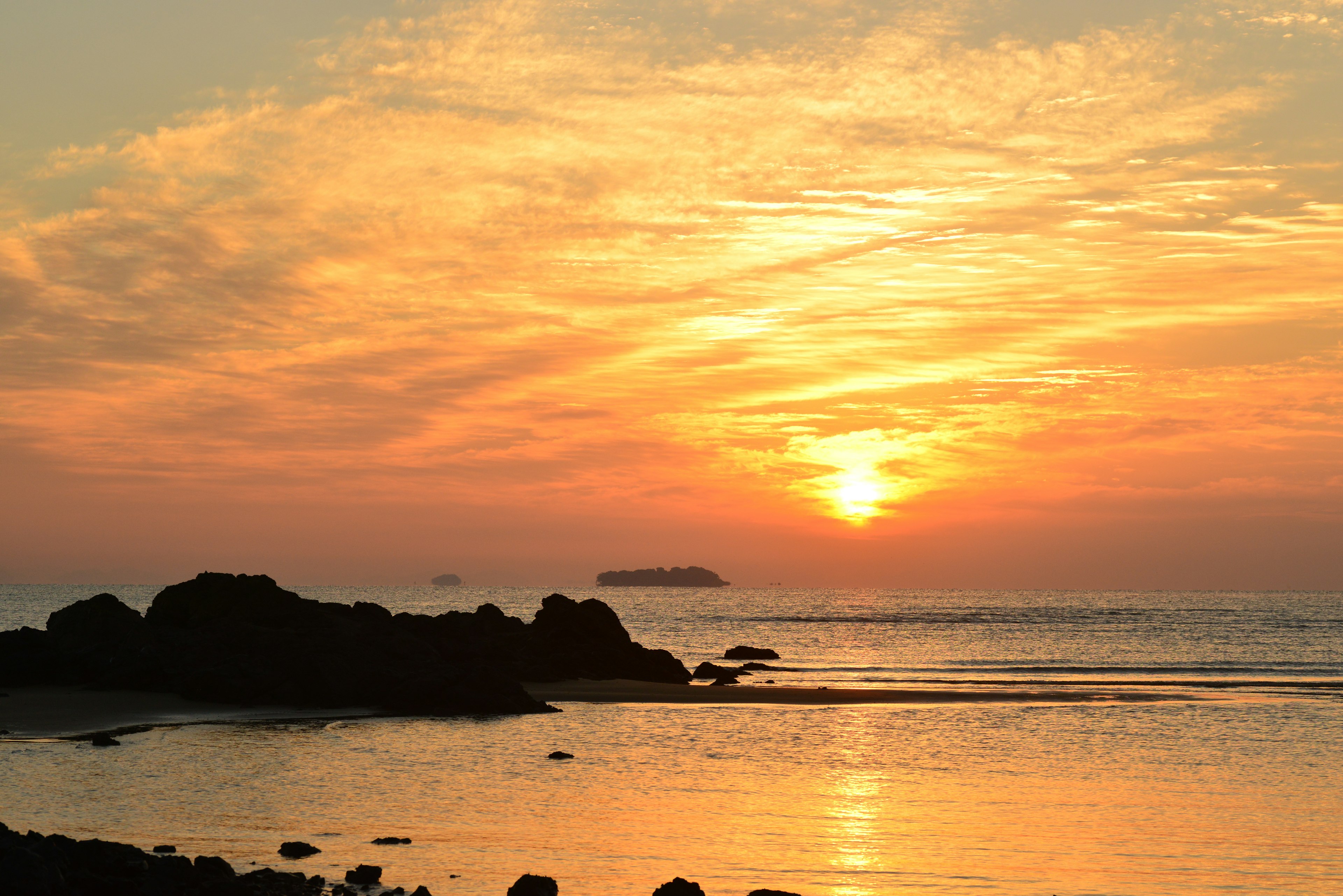 Hermoso atardecer sobre el océano con rocas en primer plano