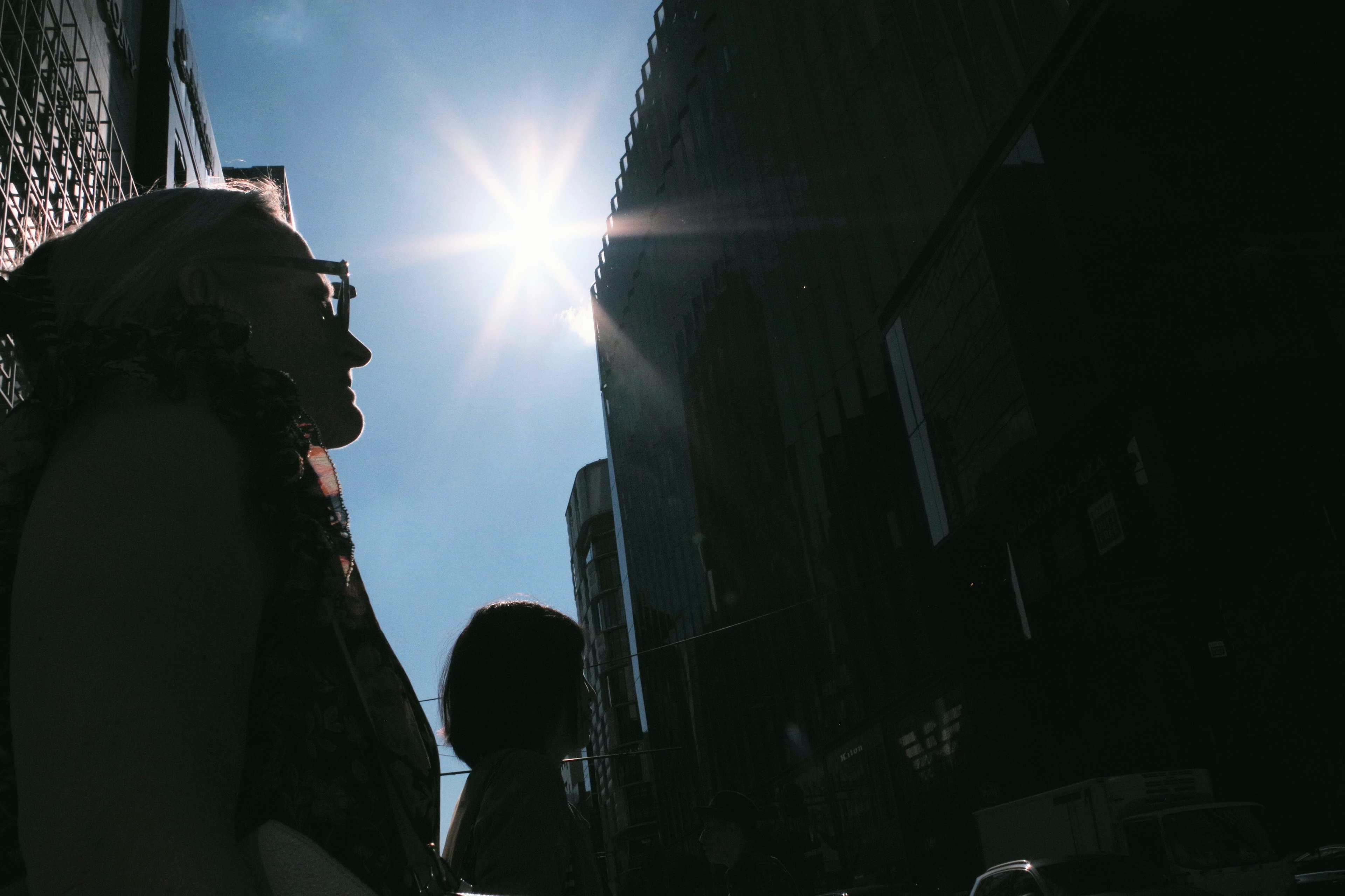 Silhouette d'une personne se tenant dans un paysage urbain sous un soleil éclatant