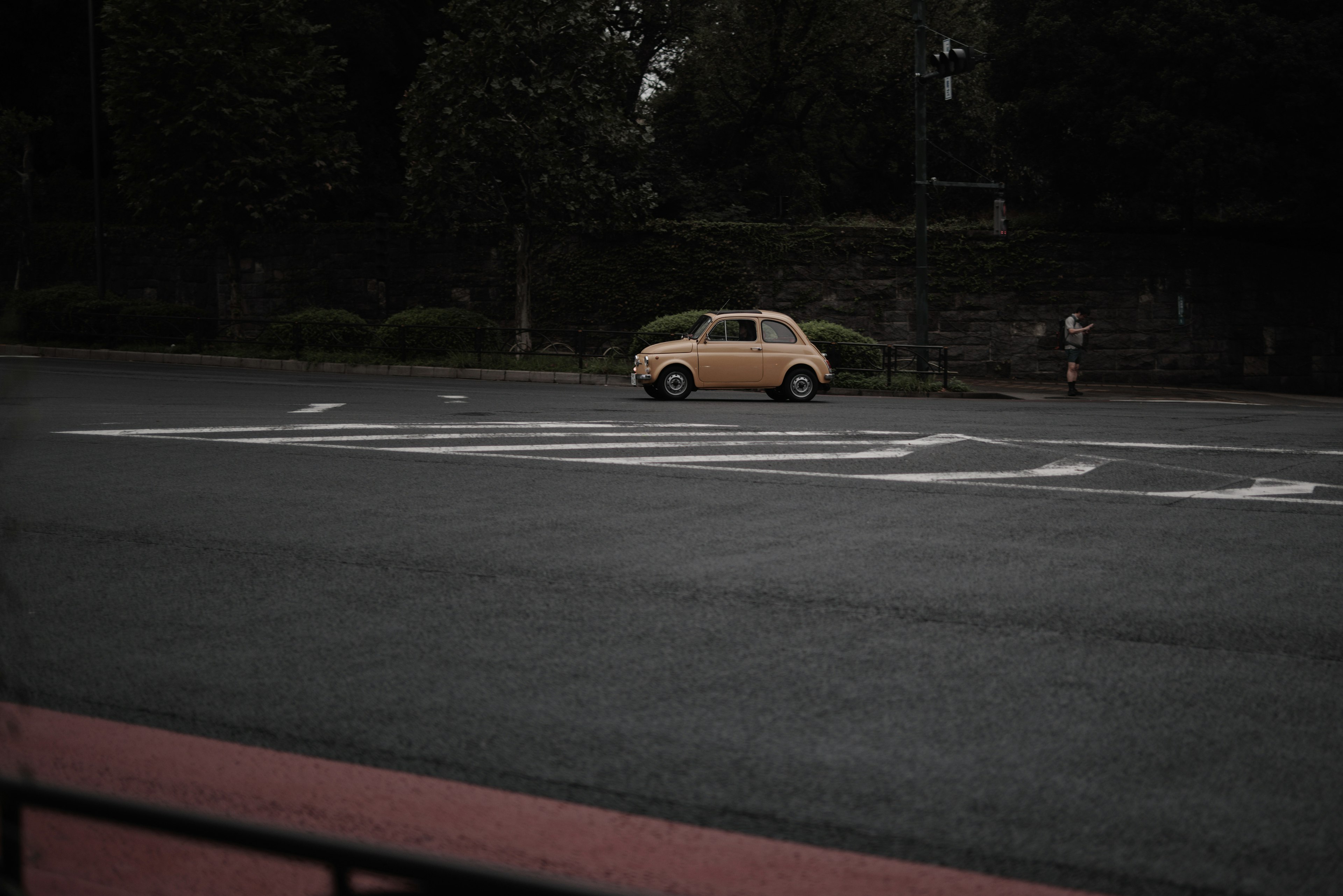 A yellow car parked on a dark road with trees in the background