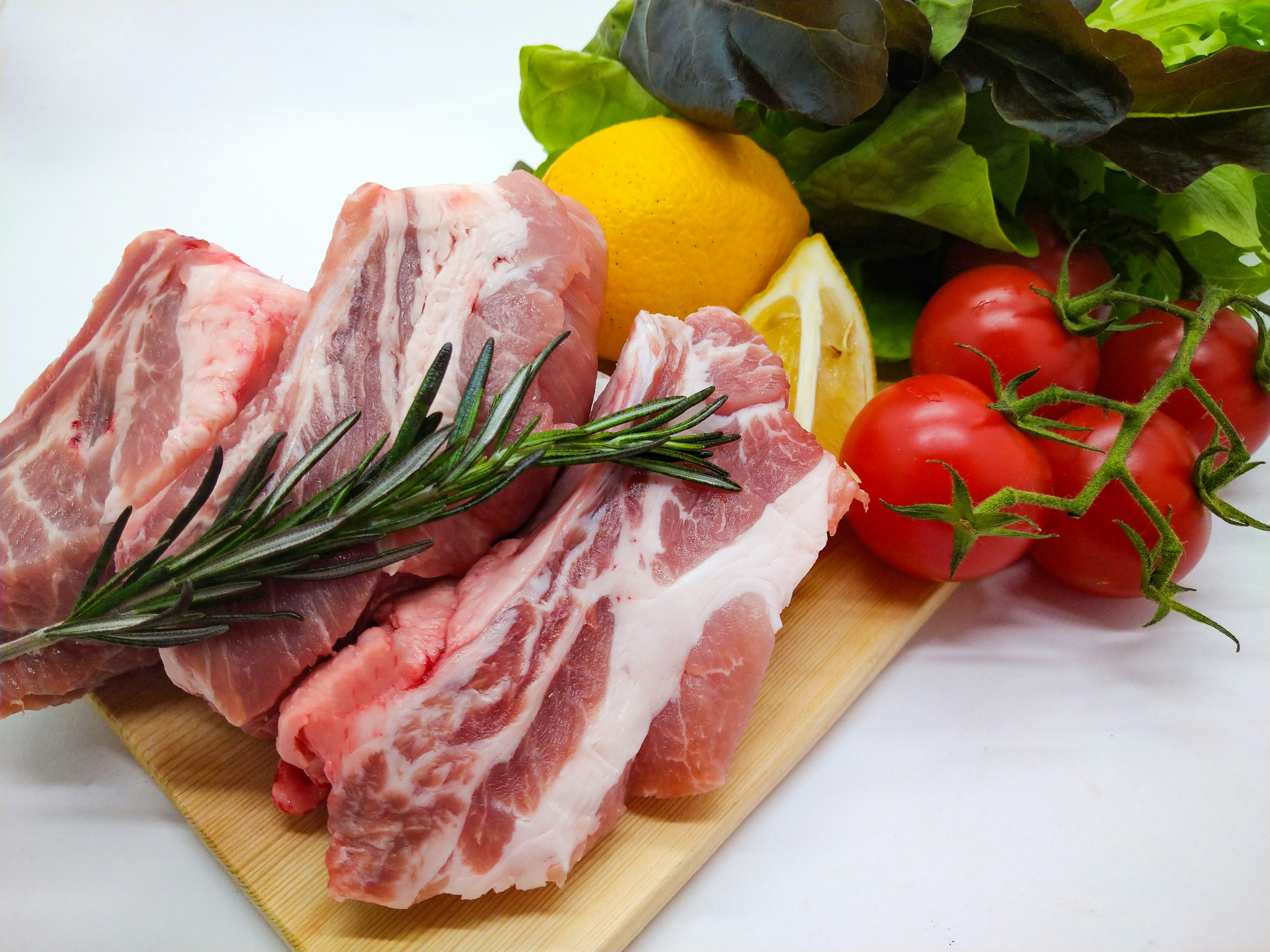 Fresh meat and vegetable arrangement with lemon, tomatoes, and rosemary