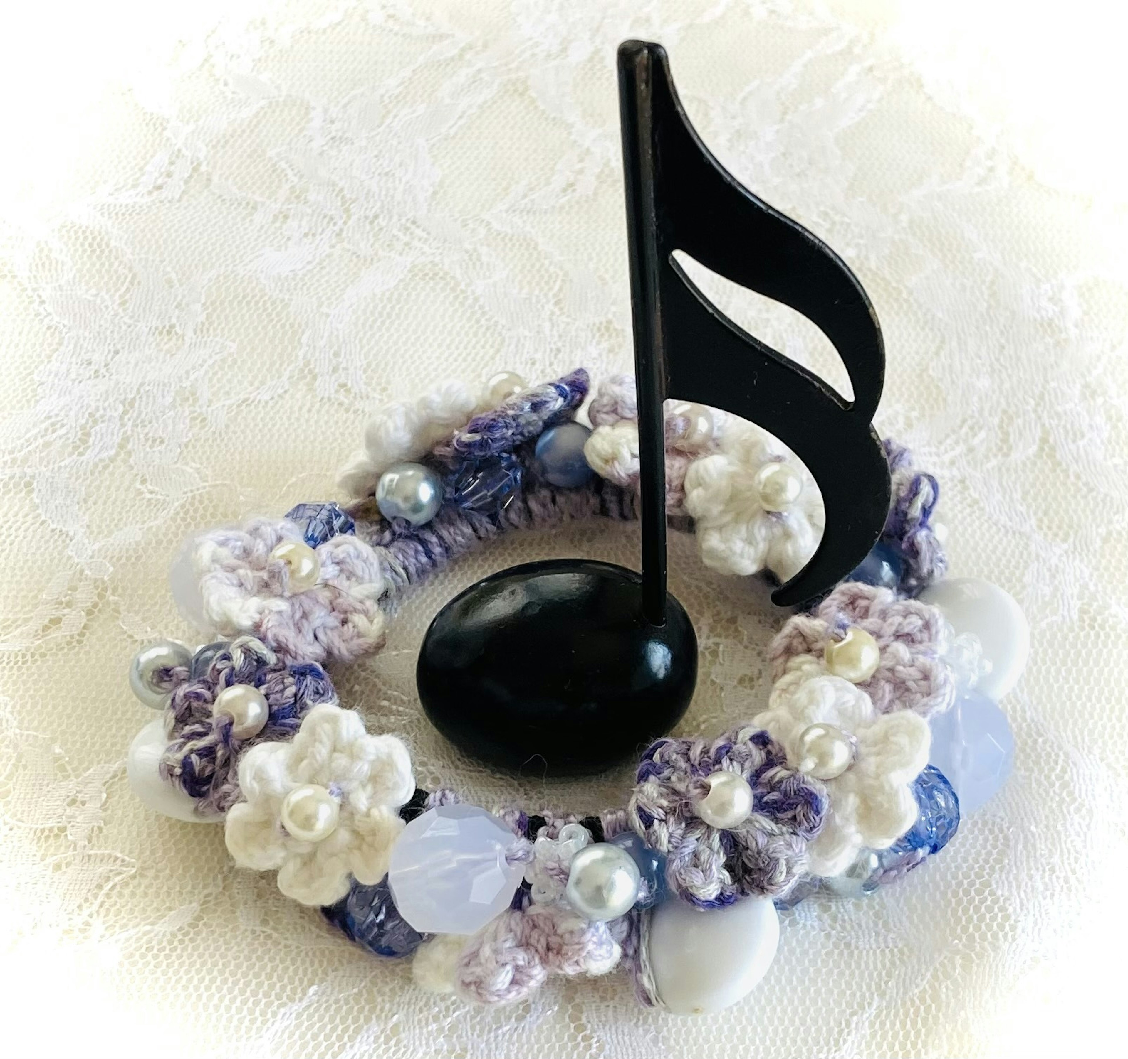 Un objet décoratif avec une note de musique noire entourée de fleurs violettes et blanches