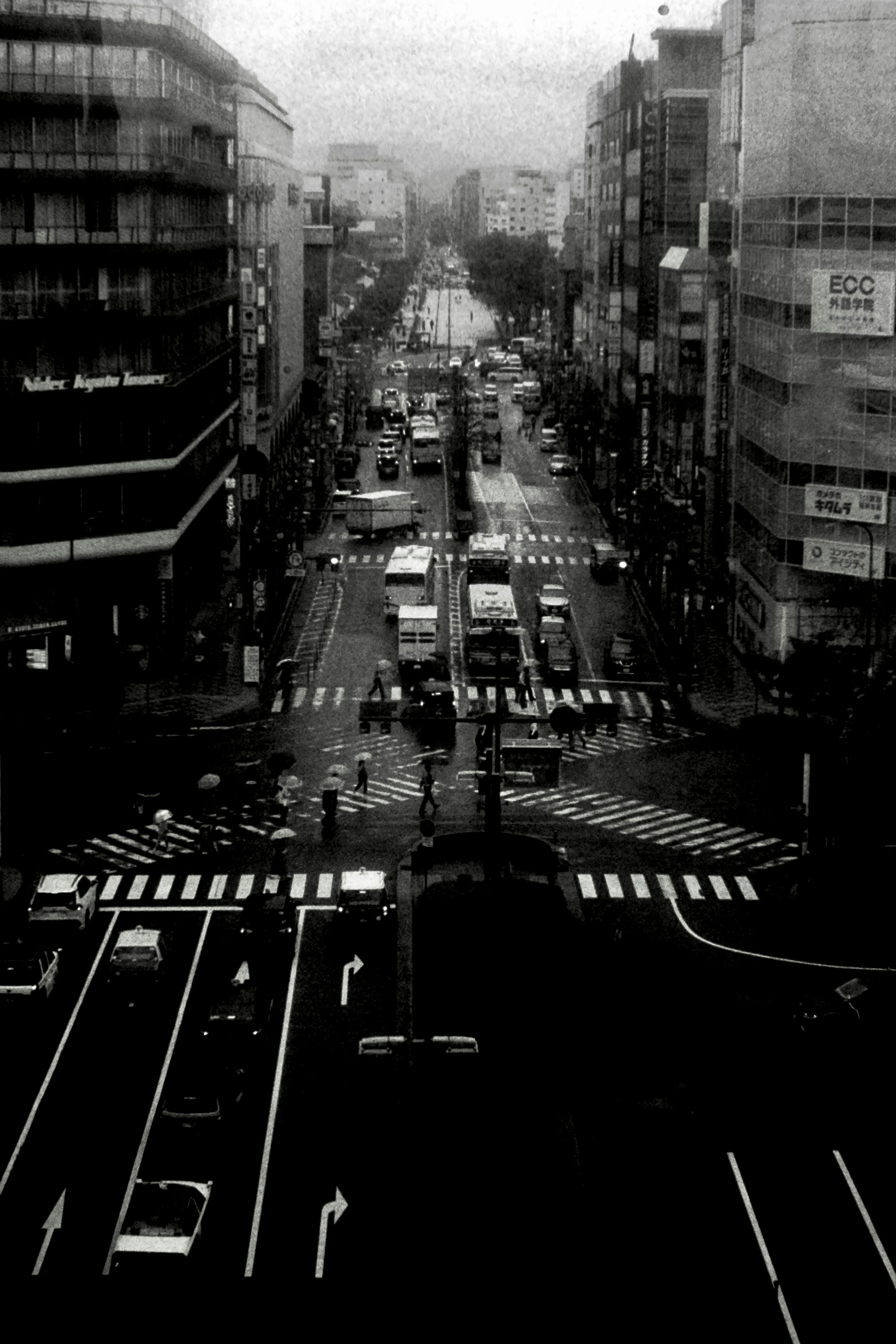 Black and white photo of an urban intersection featuring vehicles and buildings