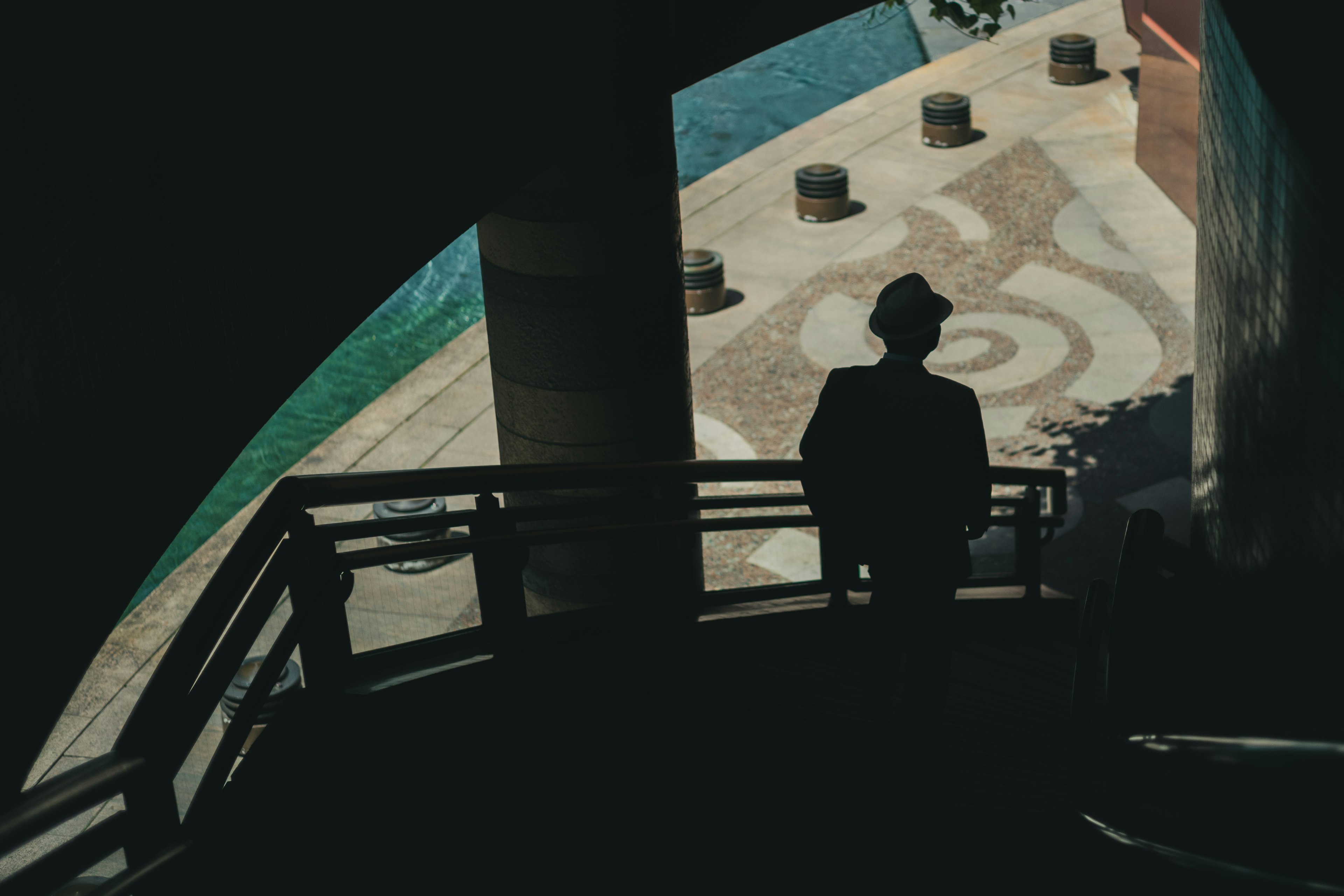 Silhouette of a man on a staircase with colorful water surface below