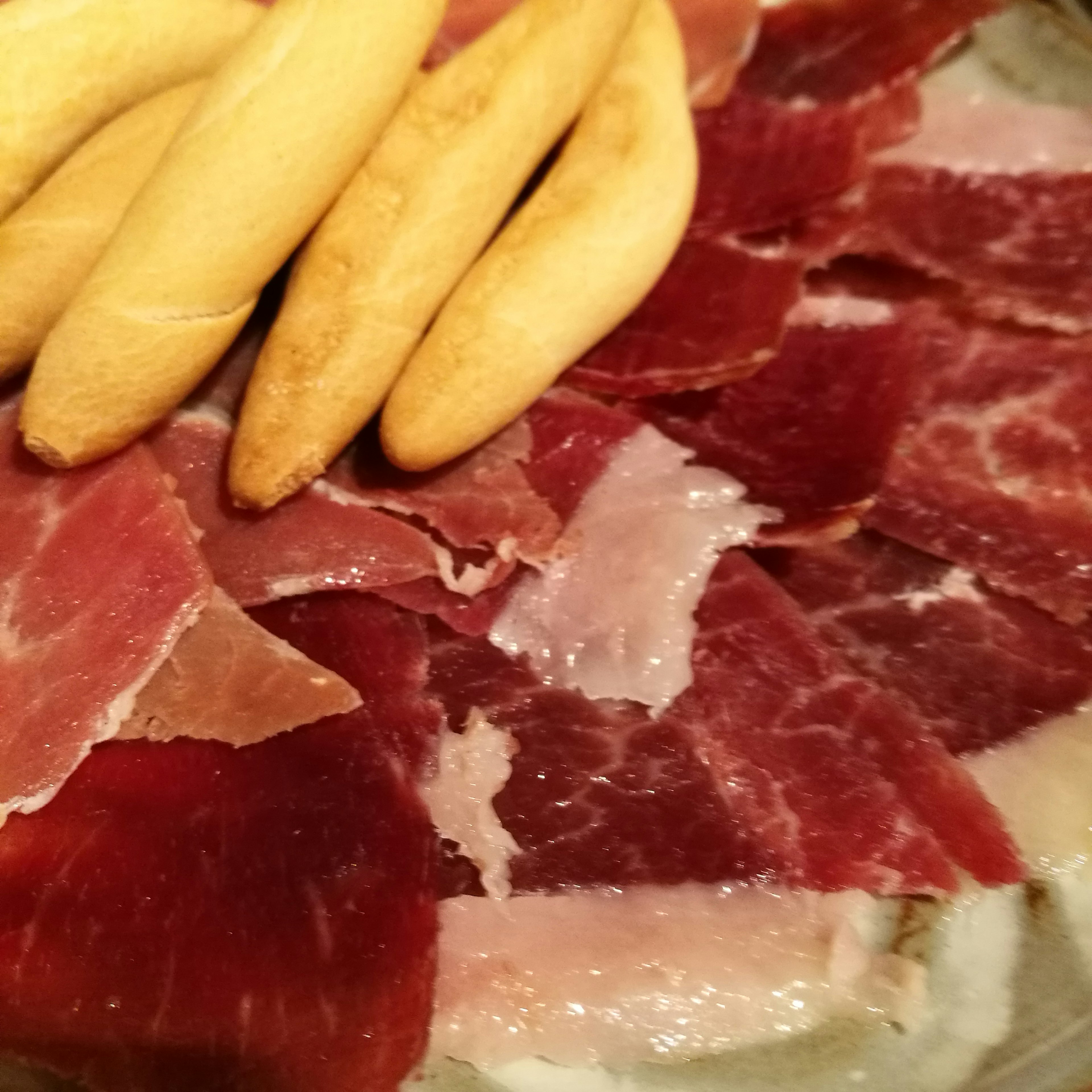 Thinly sliced cured ham with small bread pieces on a plate