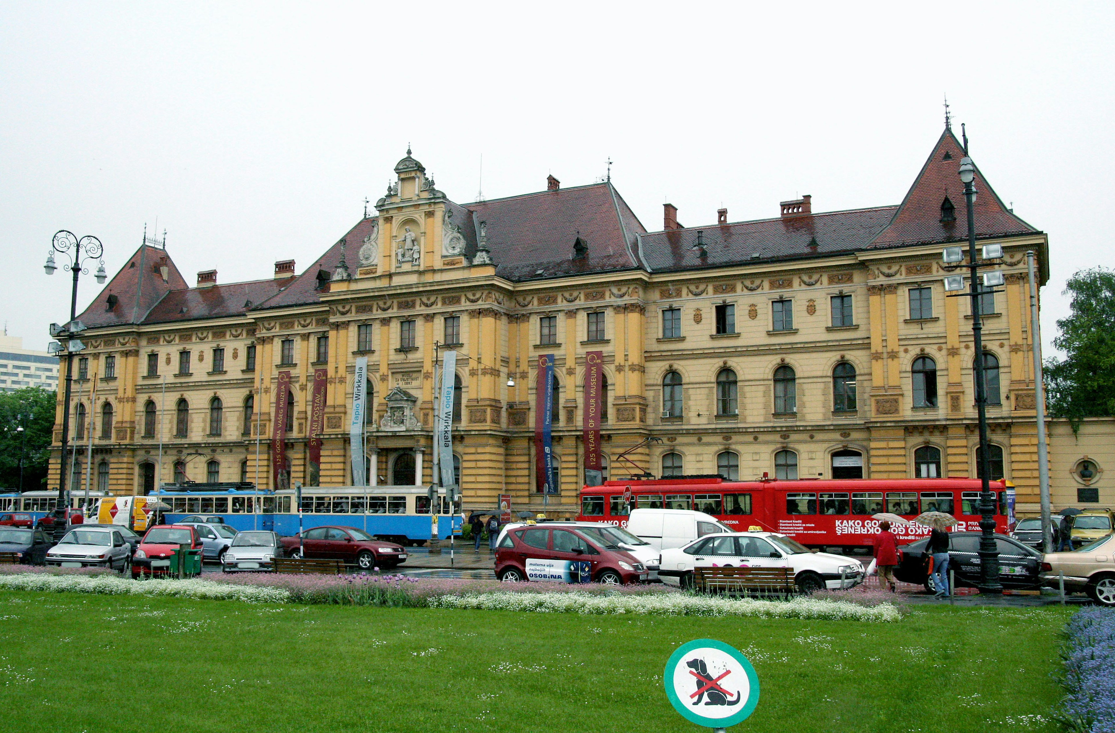 Bâtiment historique avec façade jaune et toit rouge incluant des voitures et des tramways