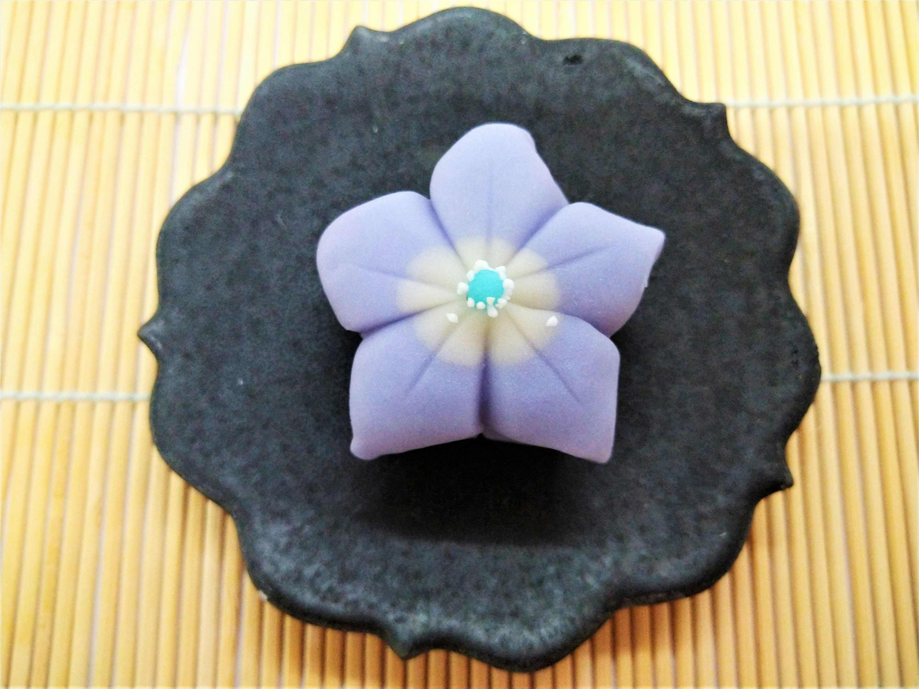 紫色の花のデザートが黒い皿に置かれている