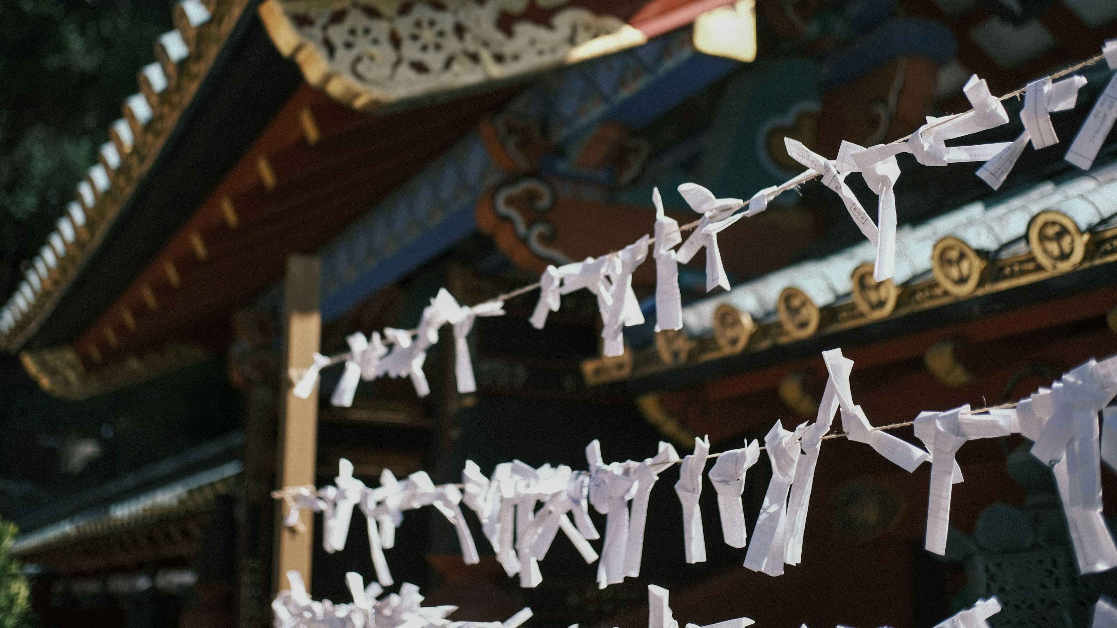 Una scena di un santuario con omikuji bianchi appesi in primo piano