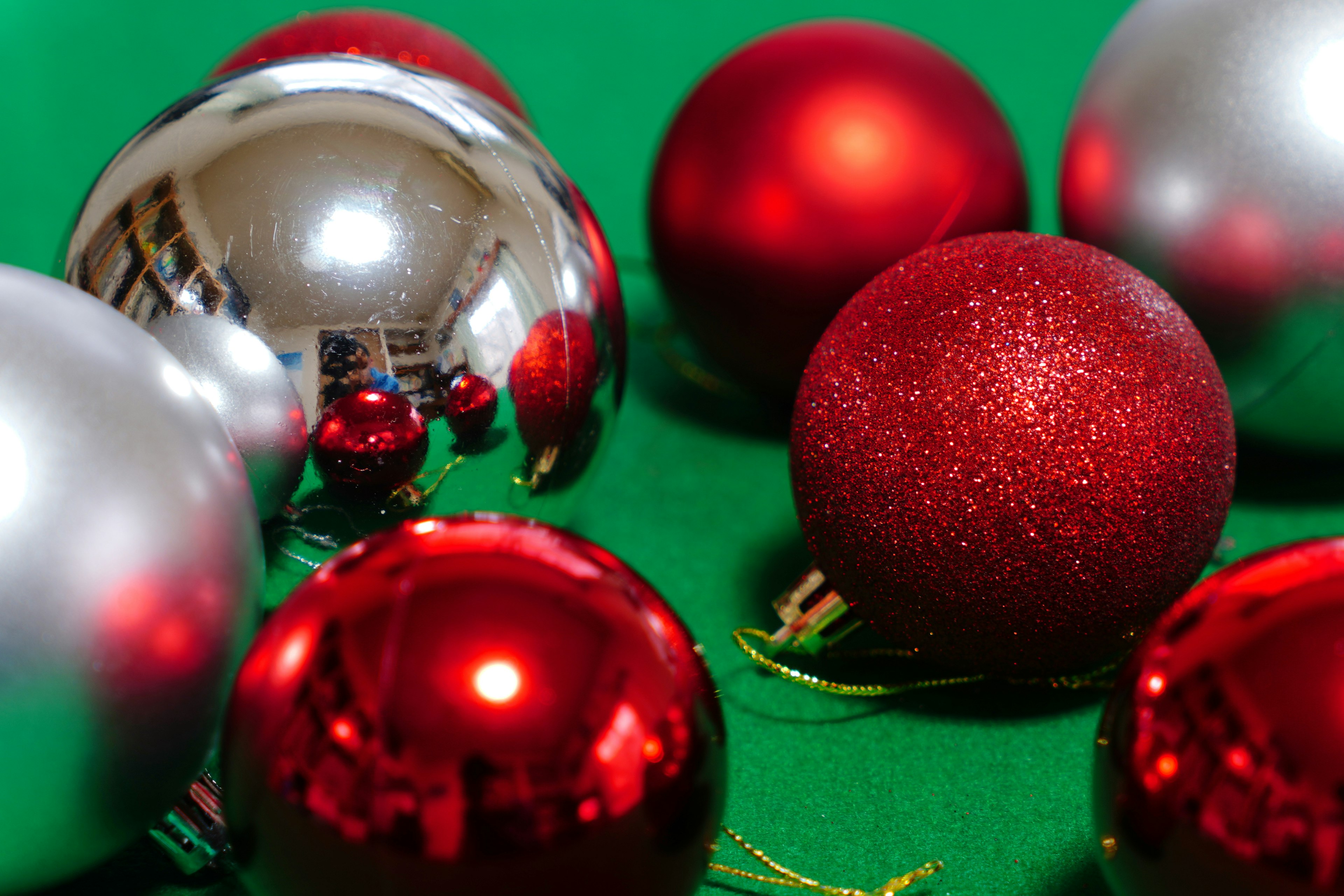 Red and silver Christmas ornaments arranged on a green background