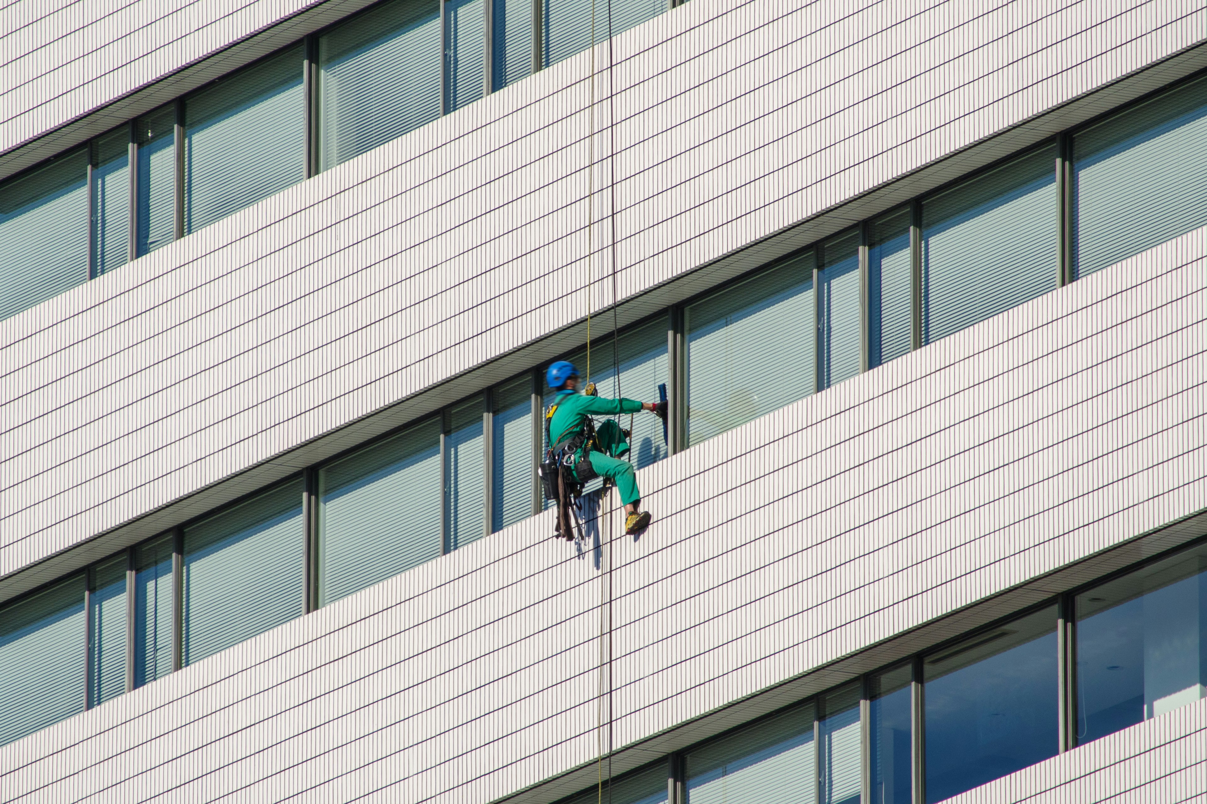 Worker descending a high-rise building wall for cleaning