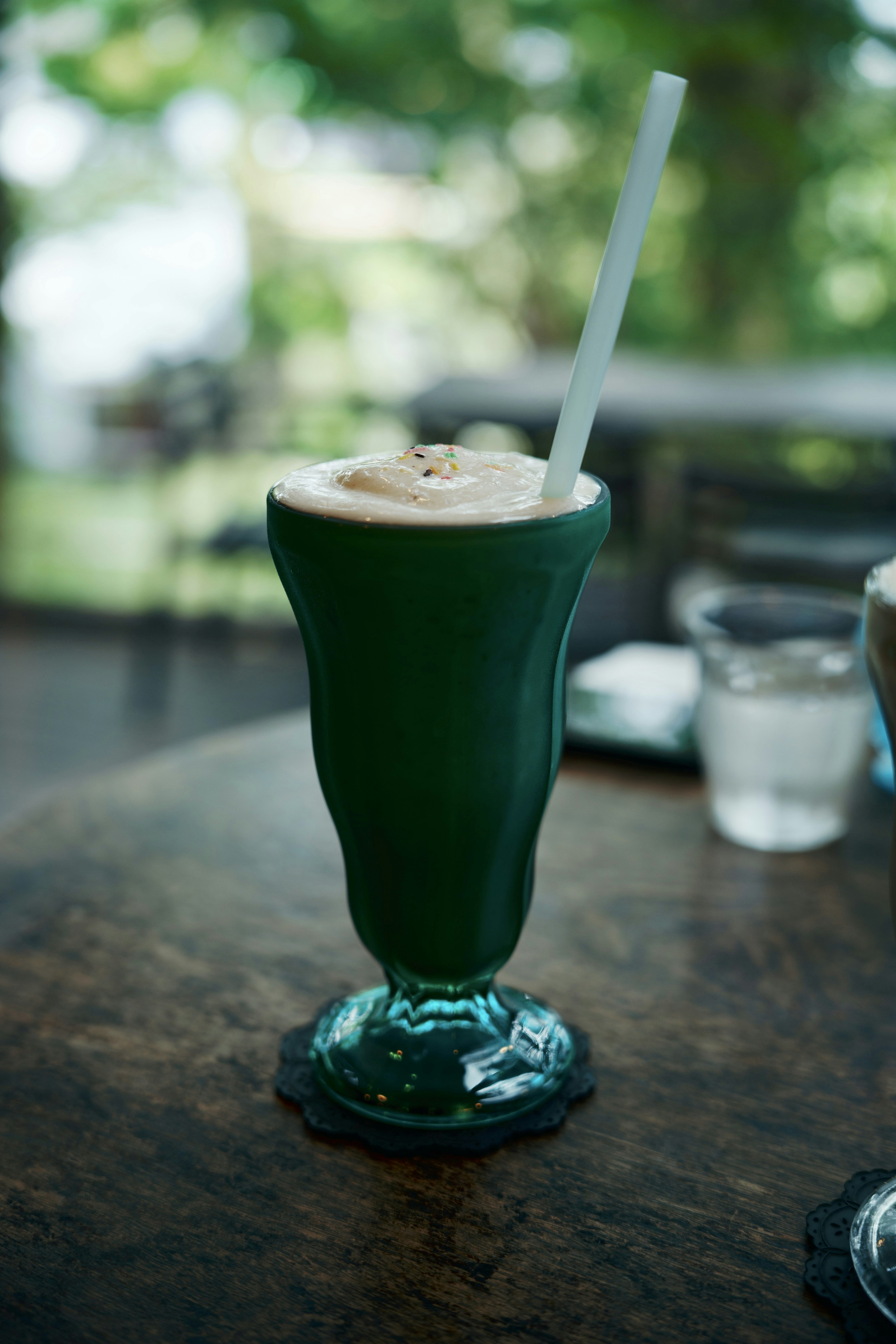 Bicchiere da cocktail verde con una bevanda e una cannuccia