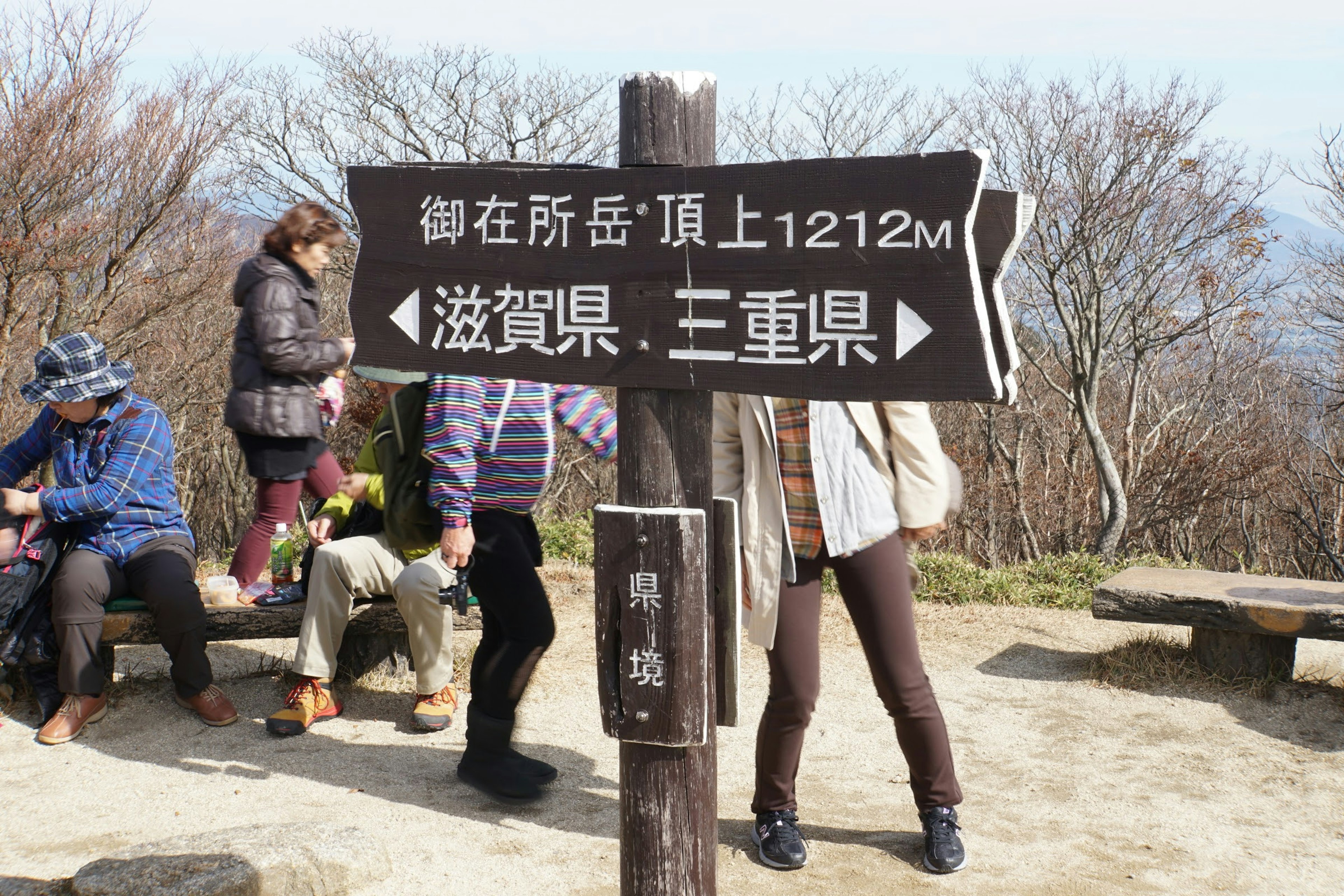 Mountain trail sign with hikers in the background