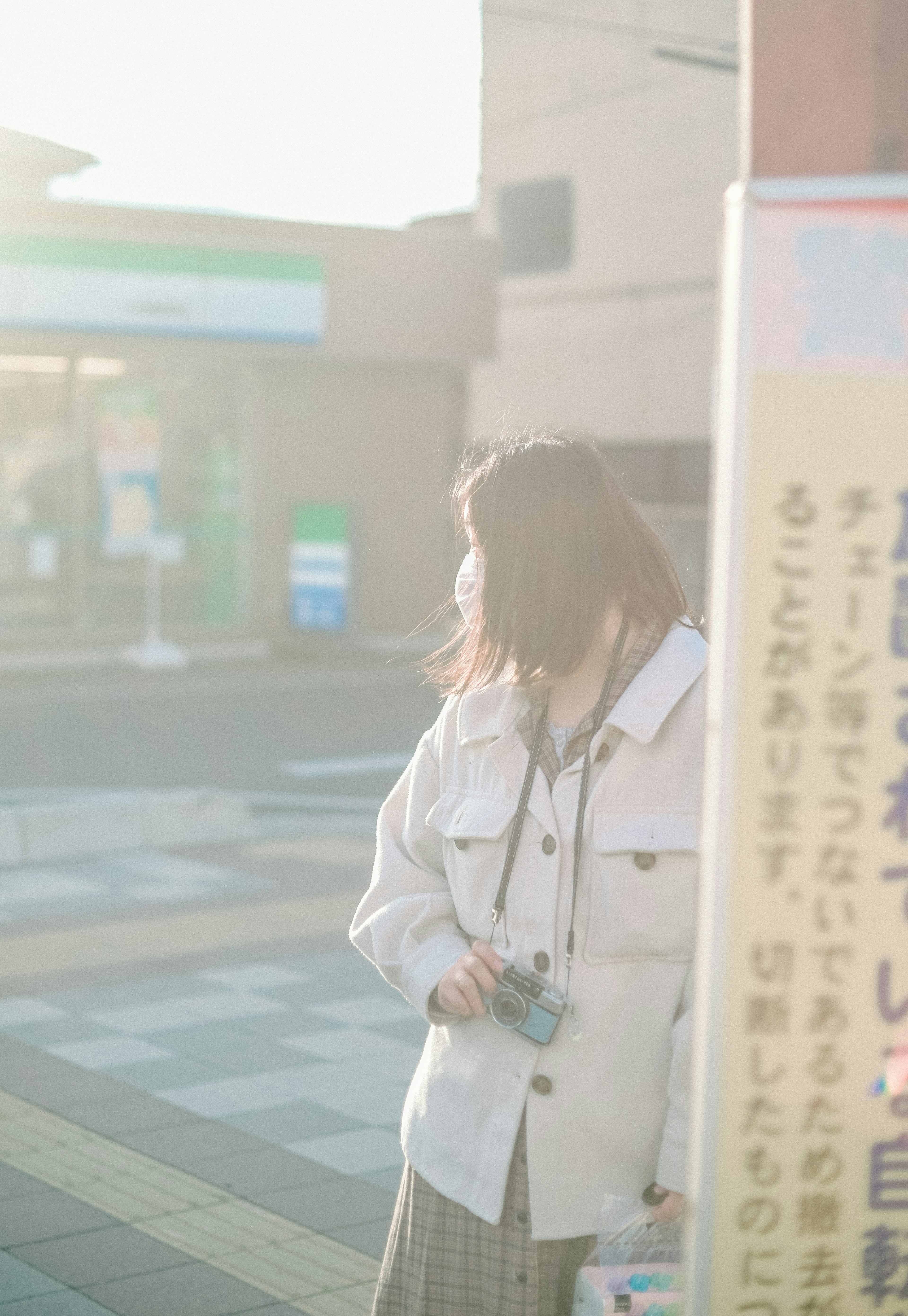 A woman in a white jacket standing in front of a sign in soft light