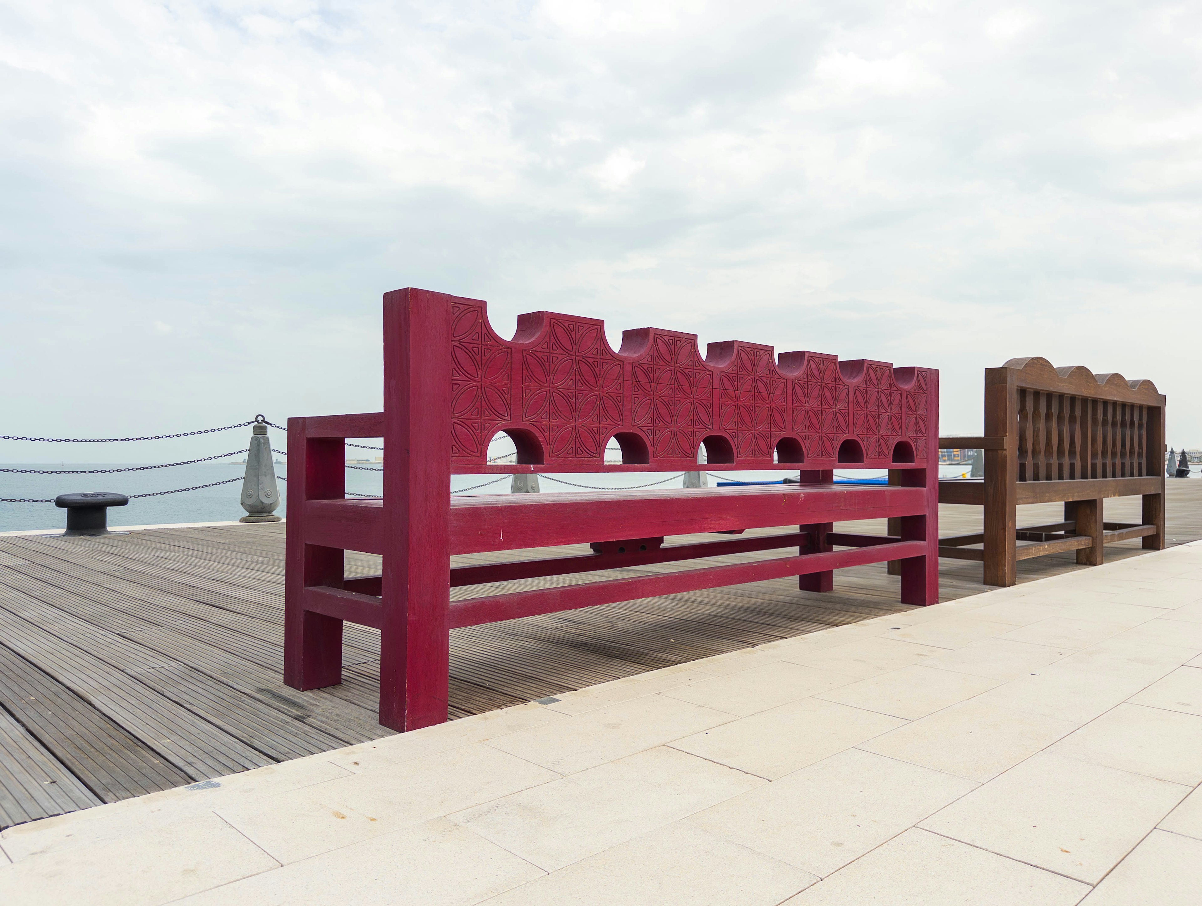 Banc rouge et banc marron sur une terrasse en bord de mer