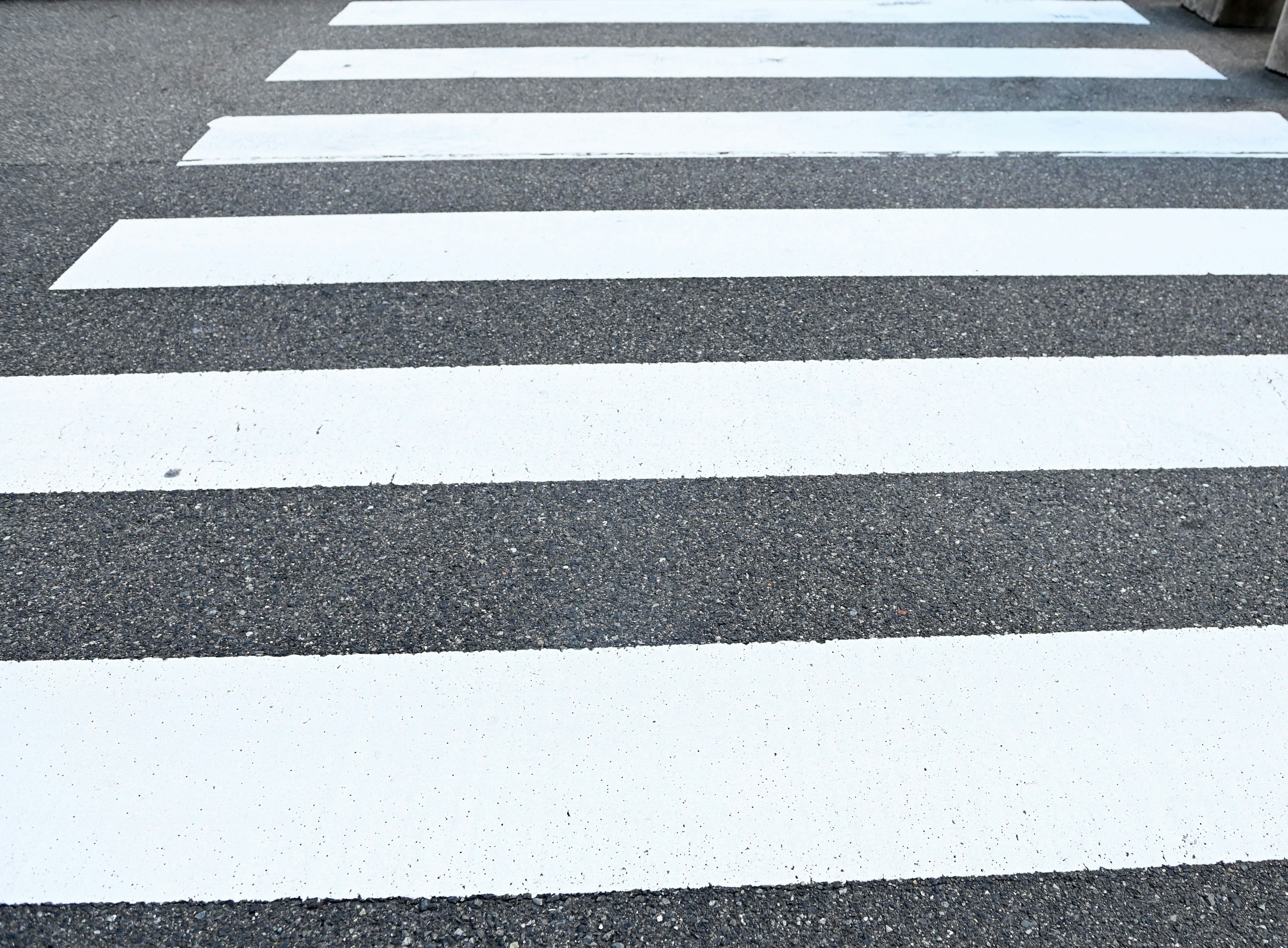 White crosswalk stripes on asphalt pavement