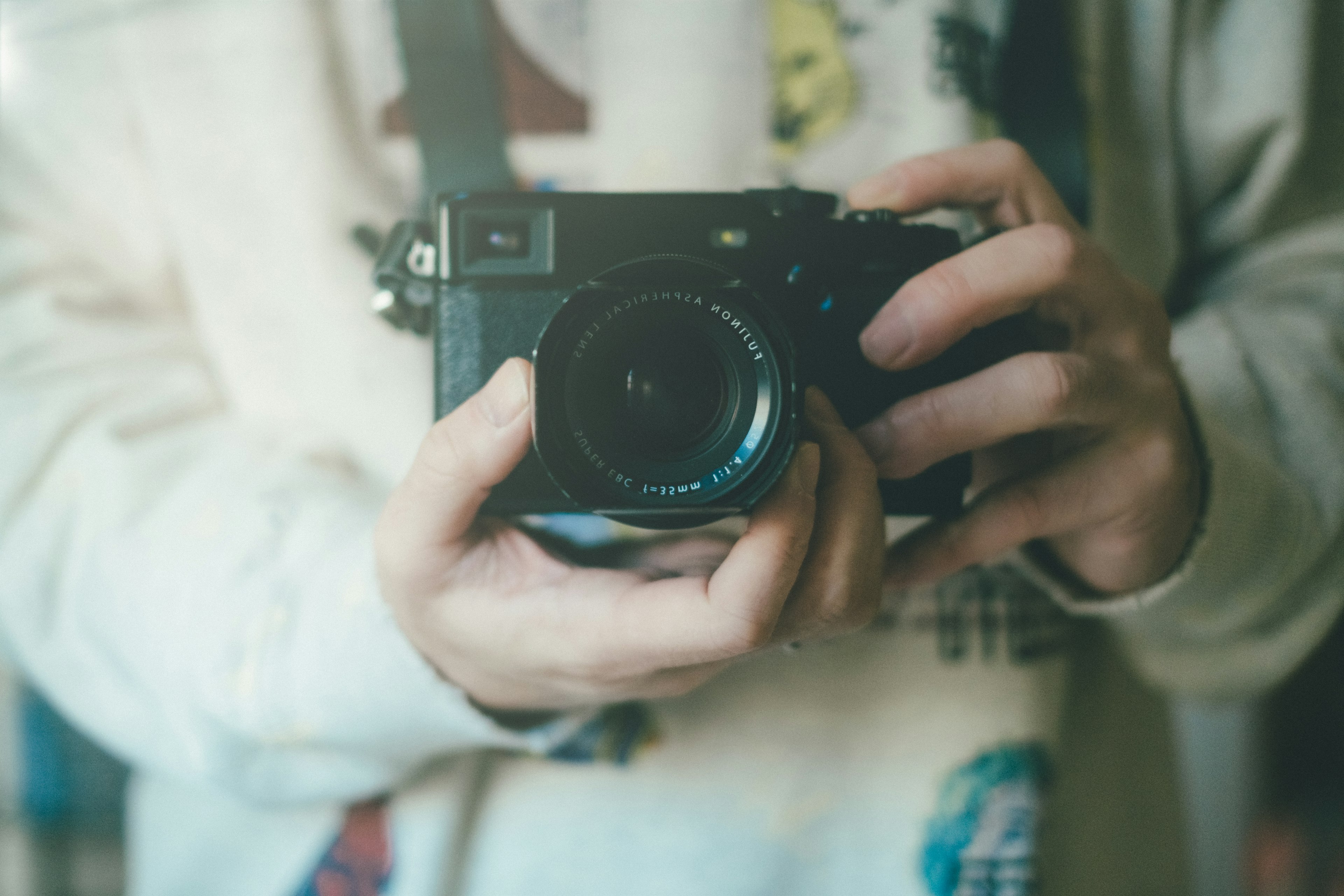 Close-up of hands holding a camera with a blurred background