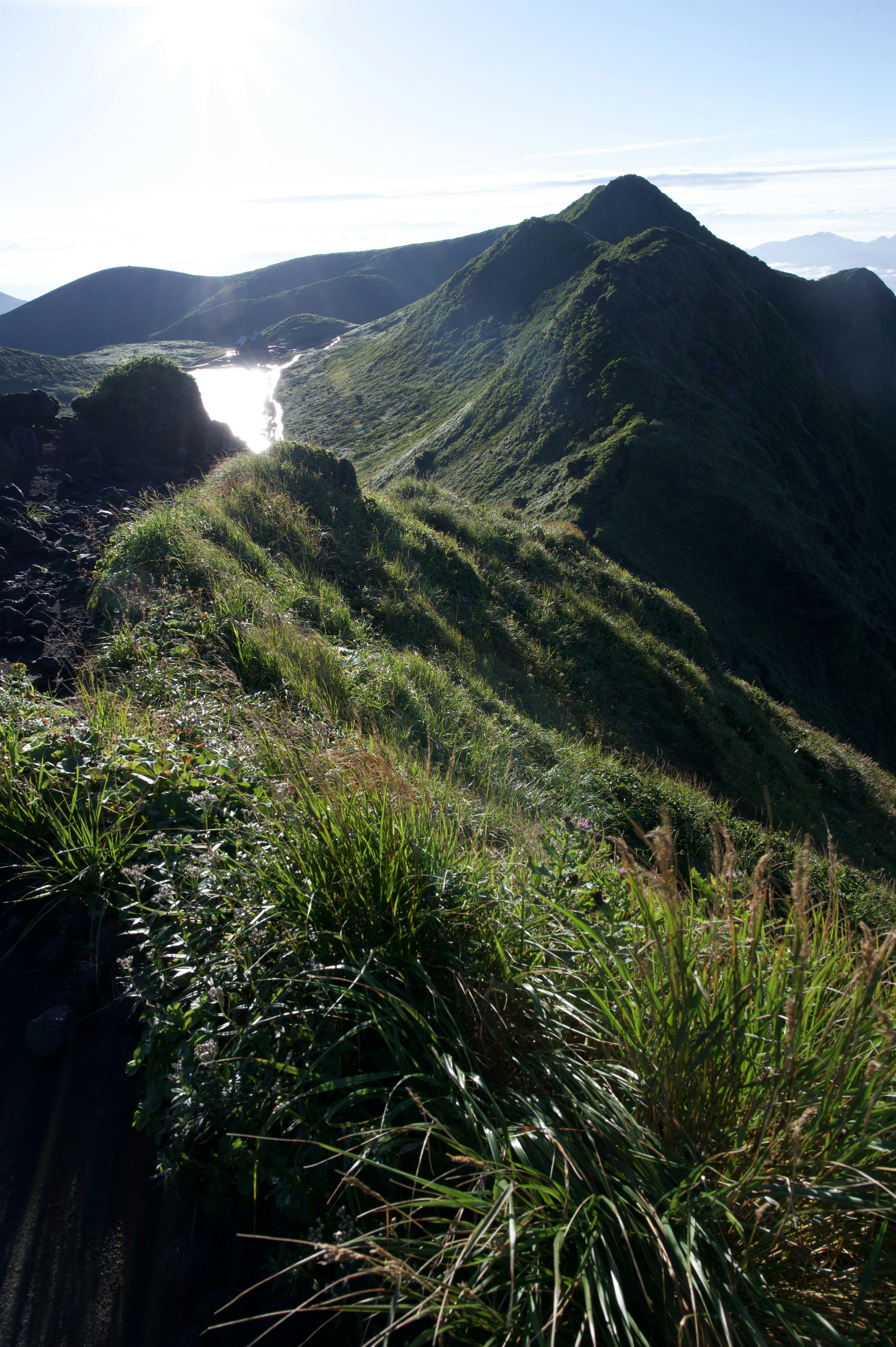 Pradera verde exuberante y crestas montañosas con un lago al fondo