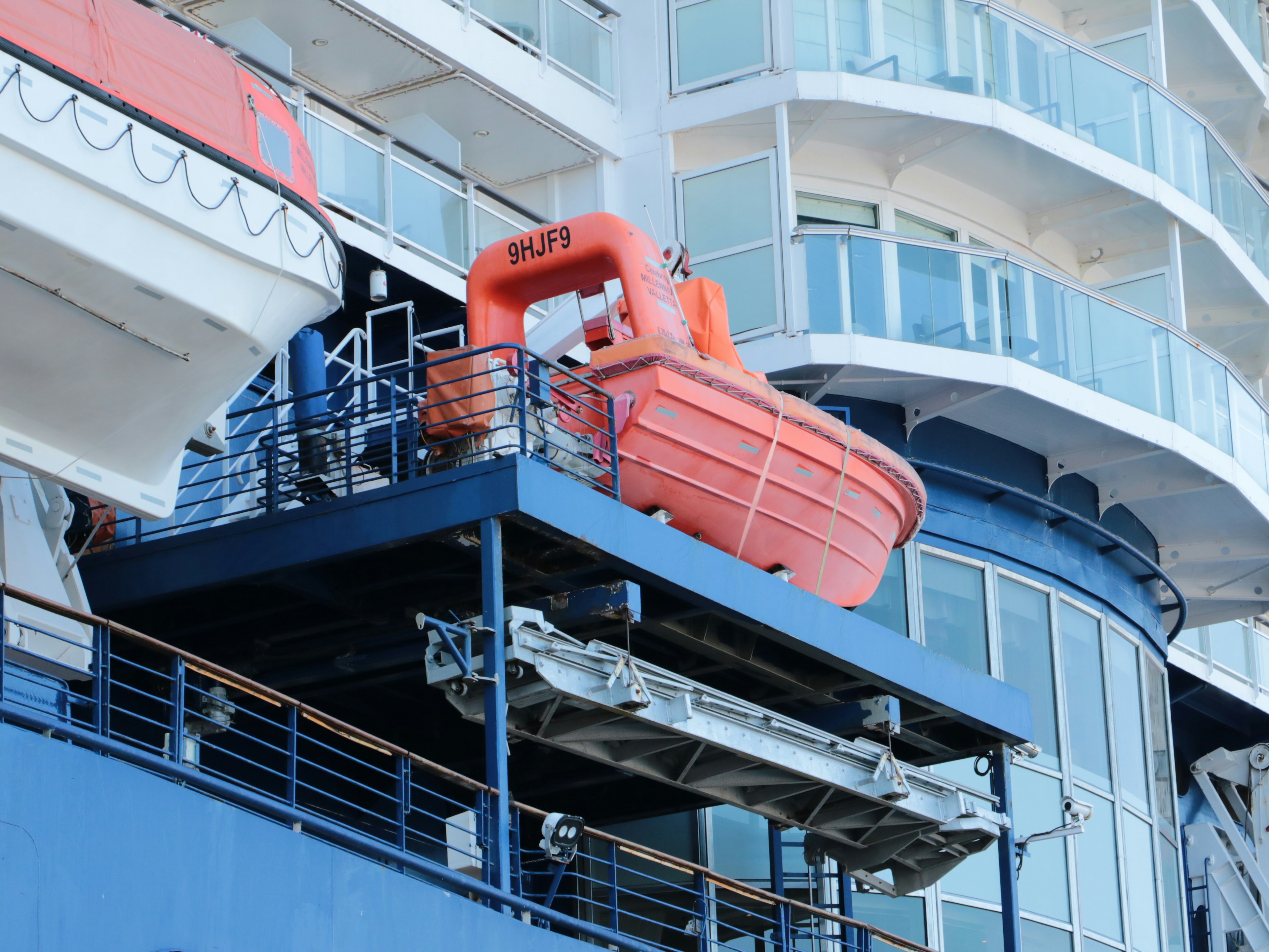 Orange lifeboat on a cruise ship with visible safety features and structure