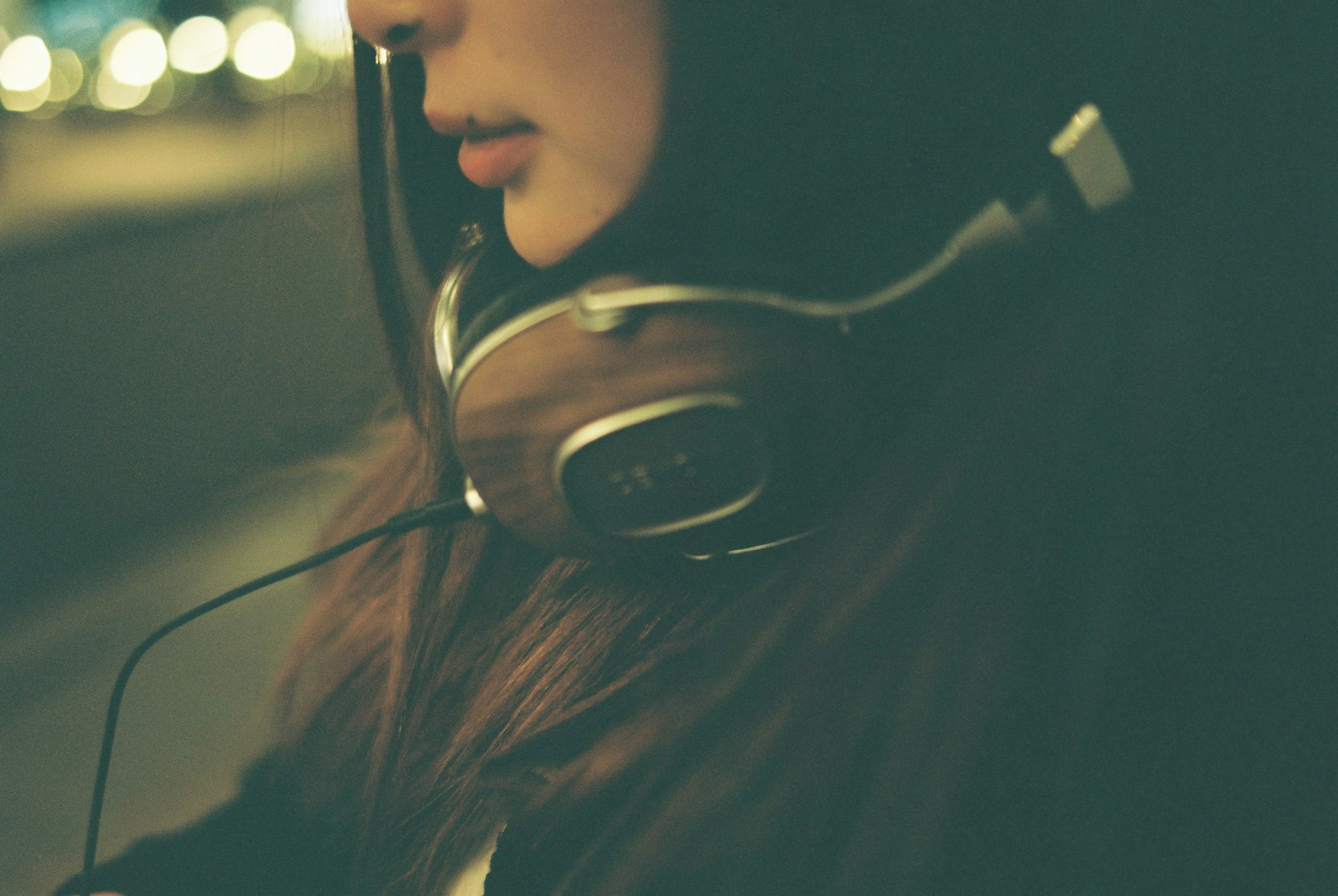 Side shot of a woman wearing headphones with a soft blurred background and a calm atmosphere