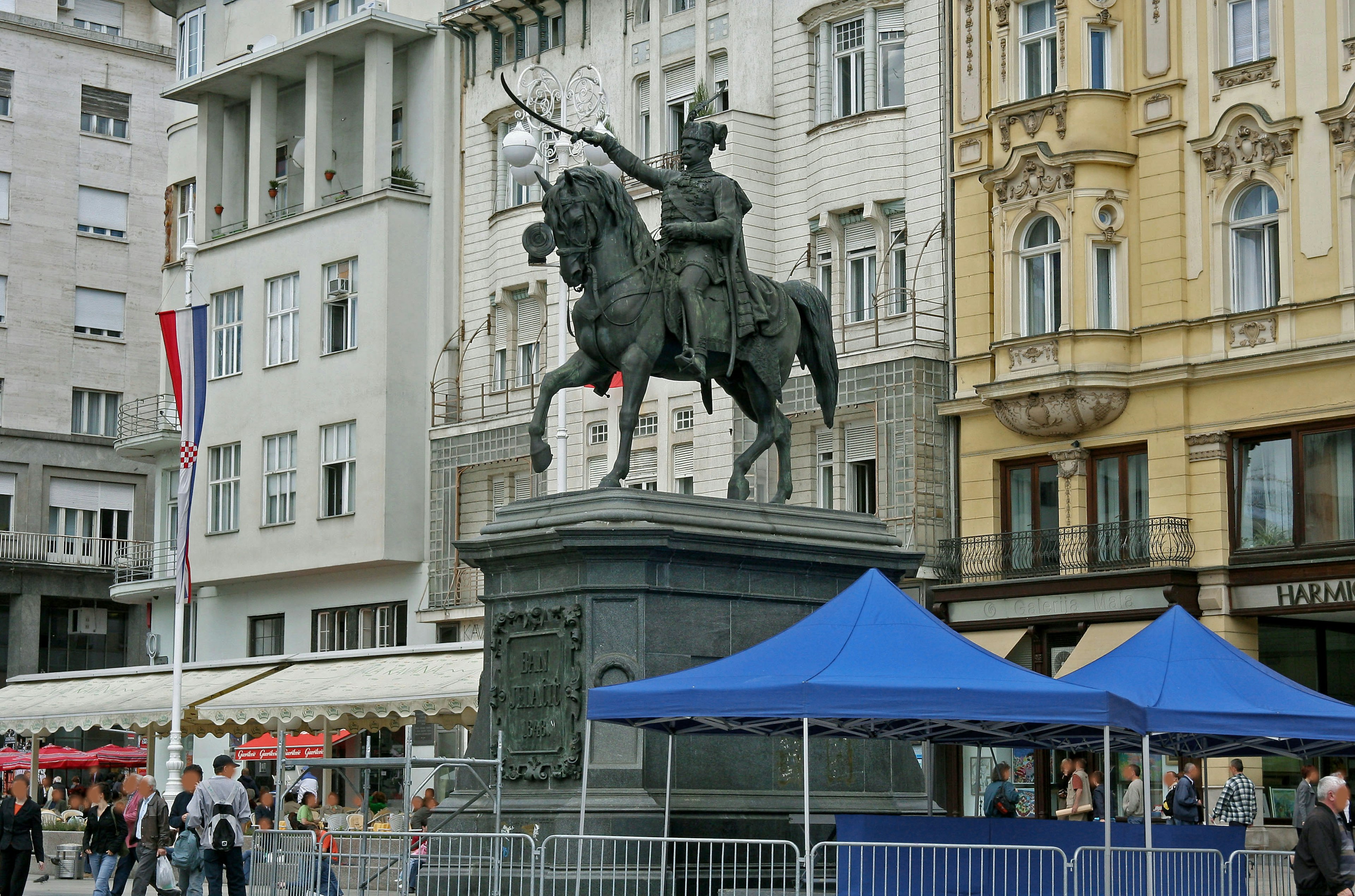 Estatua de un caballero a caballo en una plaza de la ciudad con carpas azules