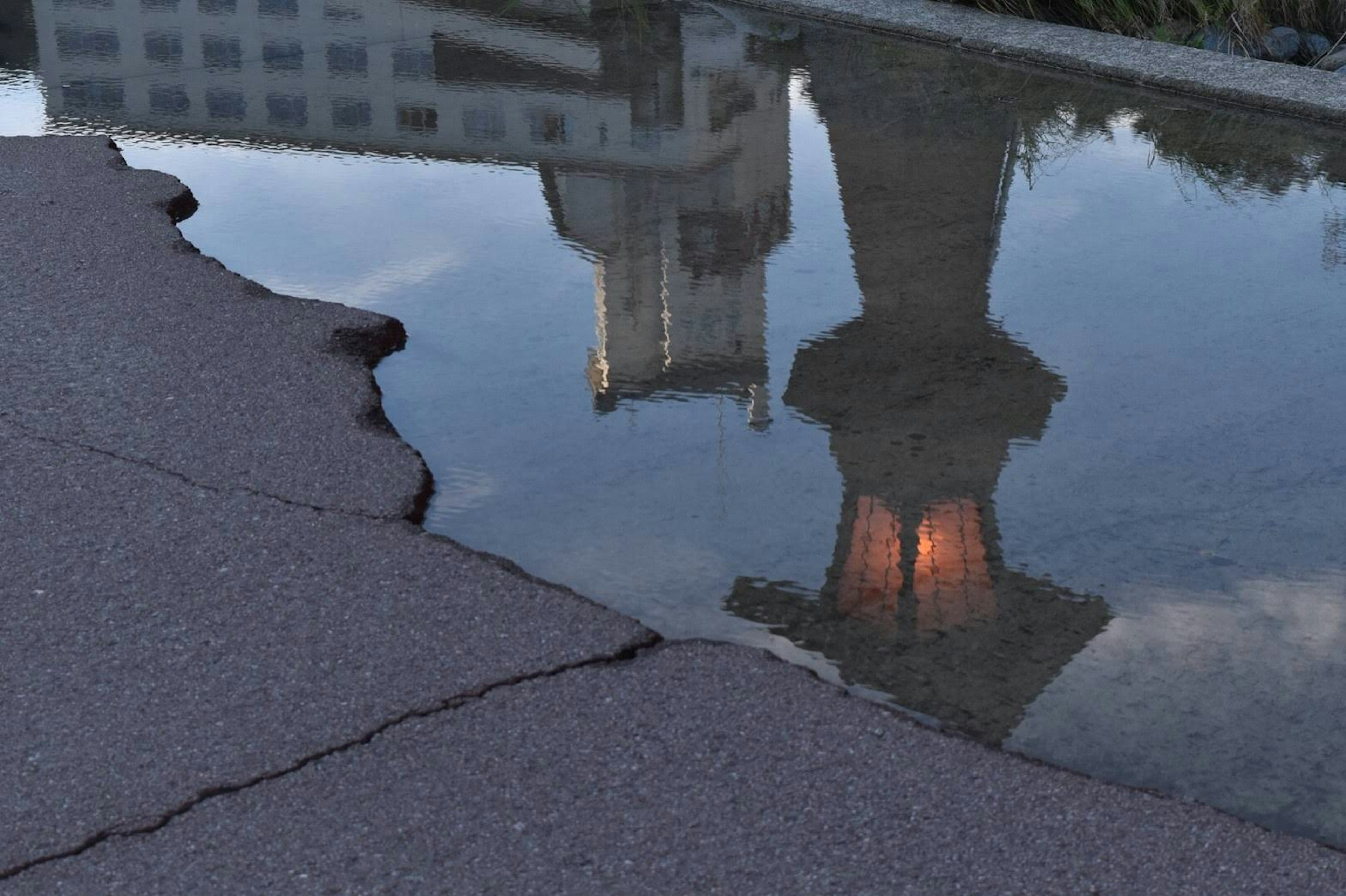 水たまりに映る建物の反射と亀裂のある地面