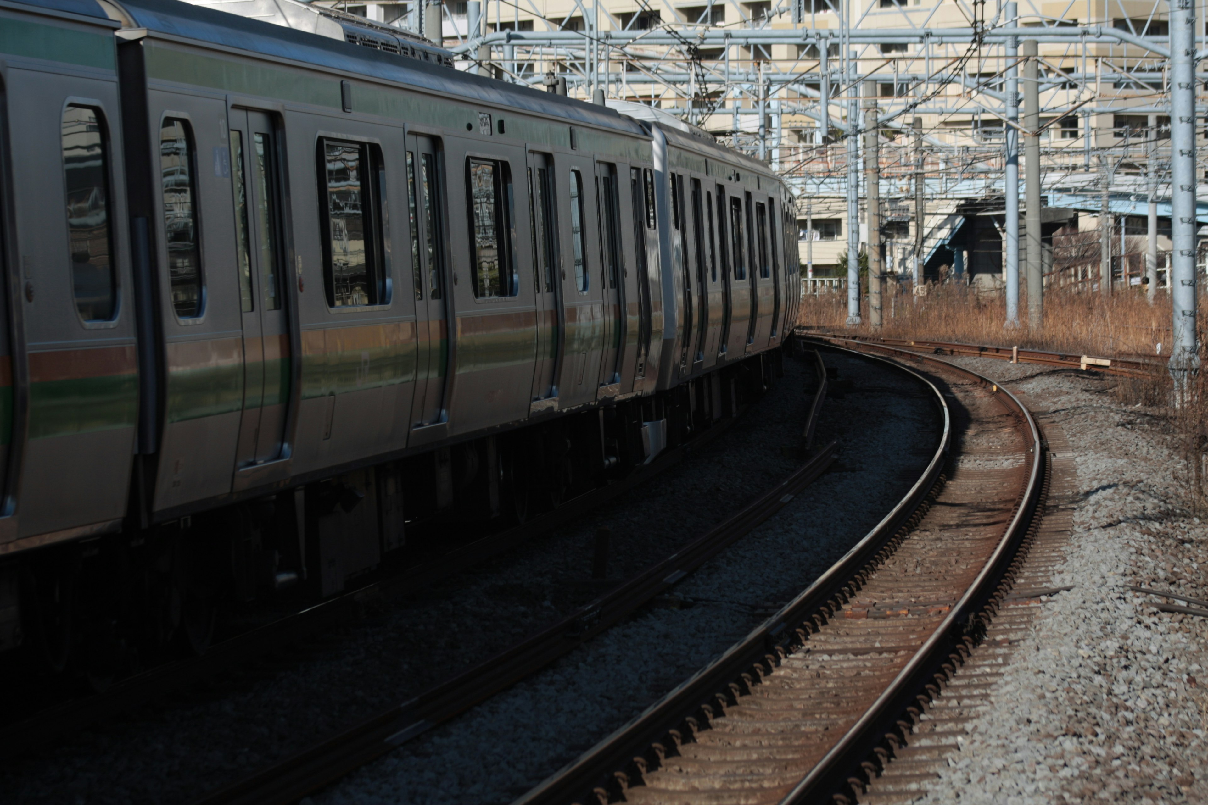 Partie d'un train près d'une voie courbée avec des bâtiments à proximité en arrière-plan