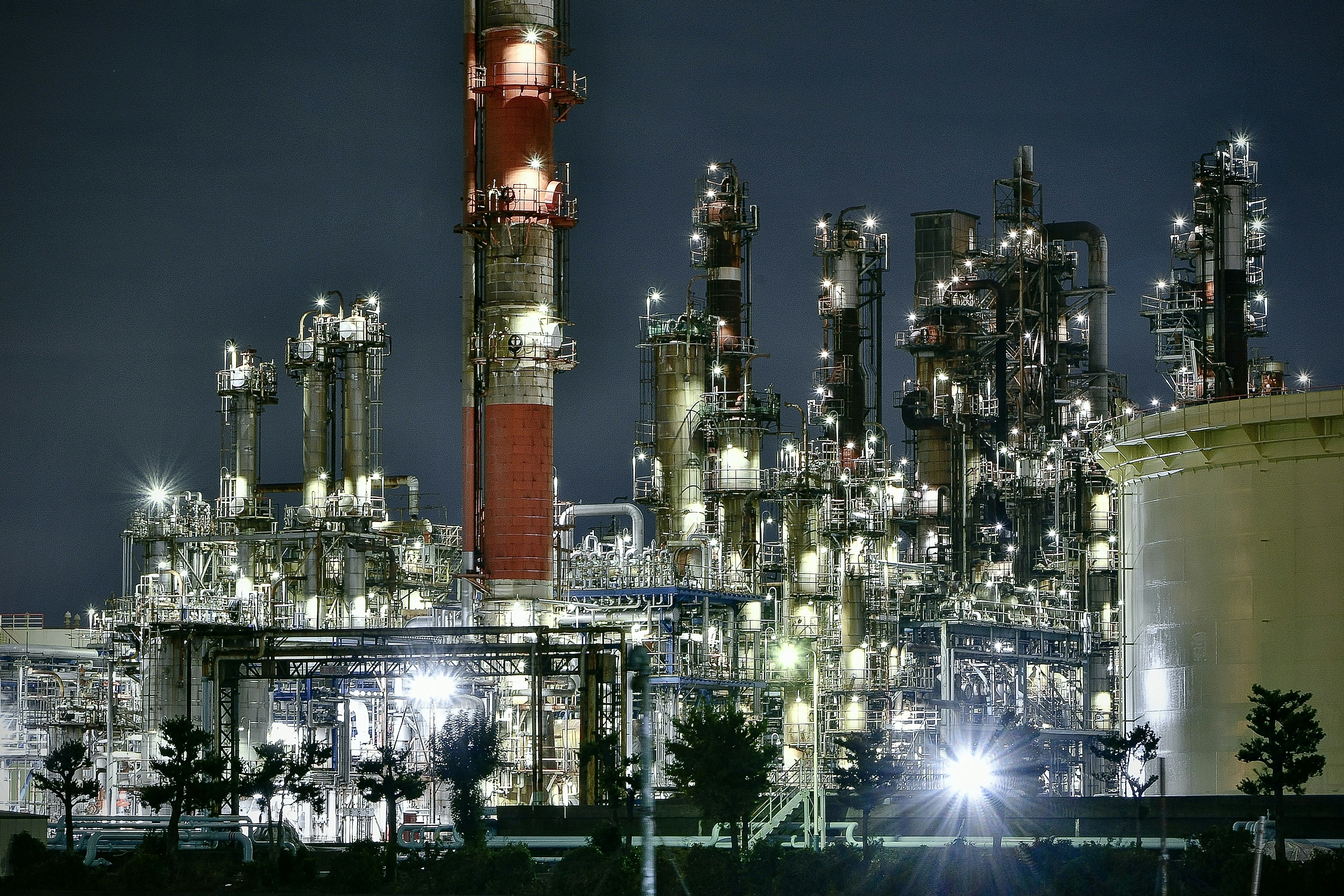 Vue nocturne d'une usine industrielle illuminée par des lumières vives