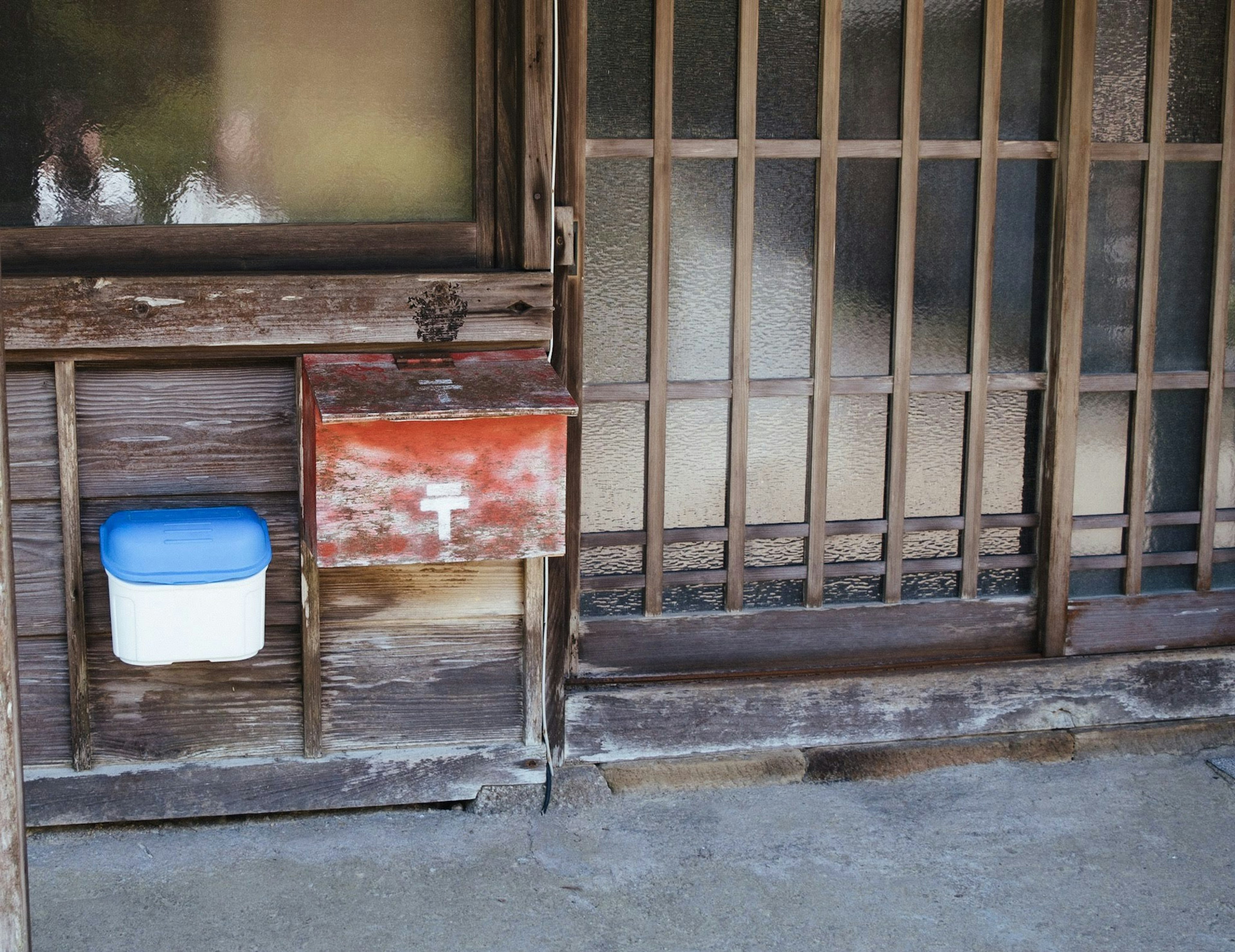 Partie d'une ancienne maison japonaise avec une boîte aux lettres et un conteneur blanc