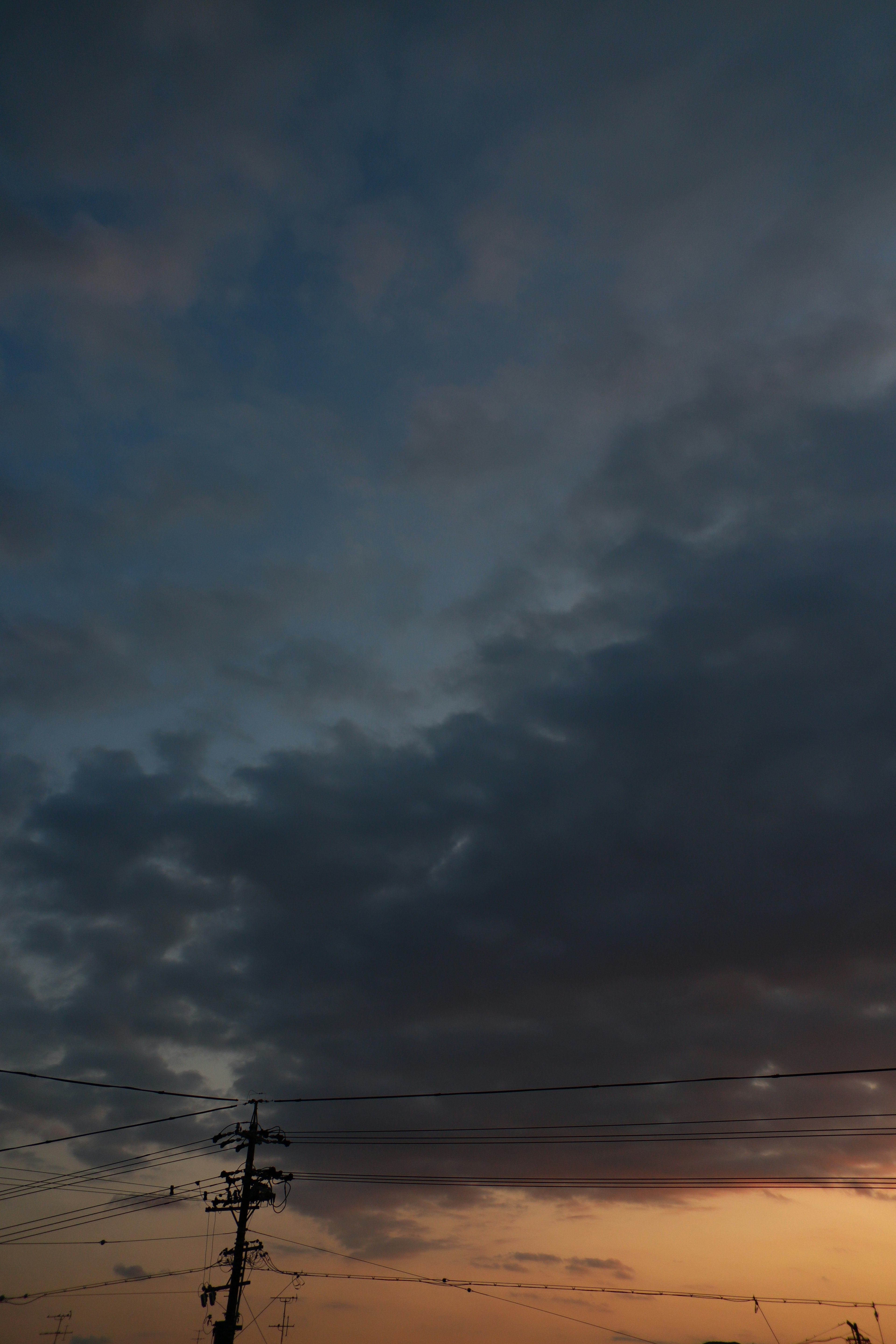 Dämmerungshimmel mit dunklen Wolken und einem Strommast