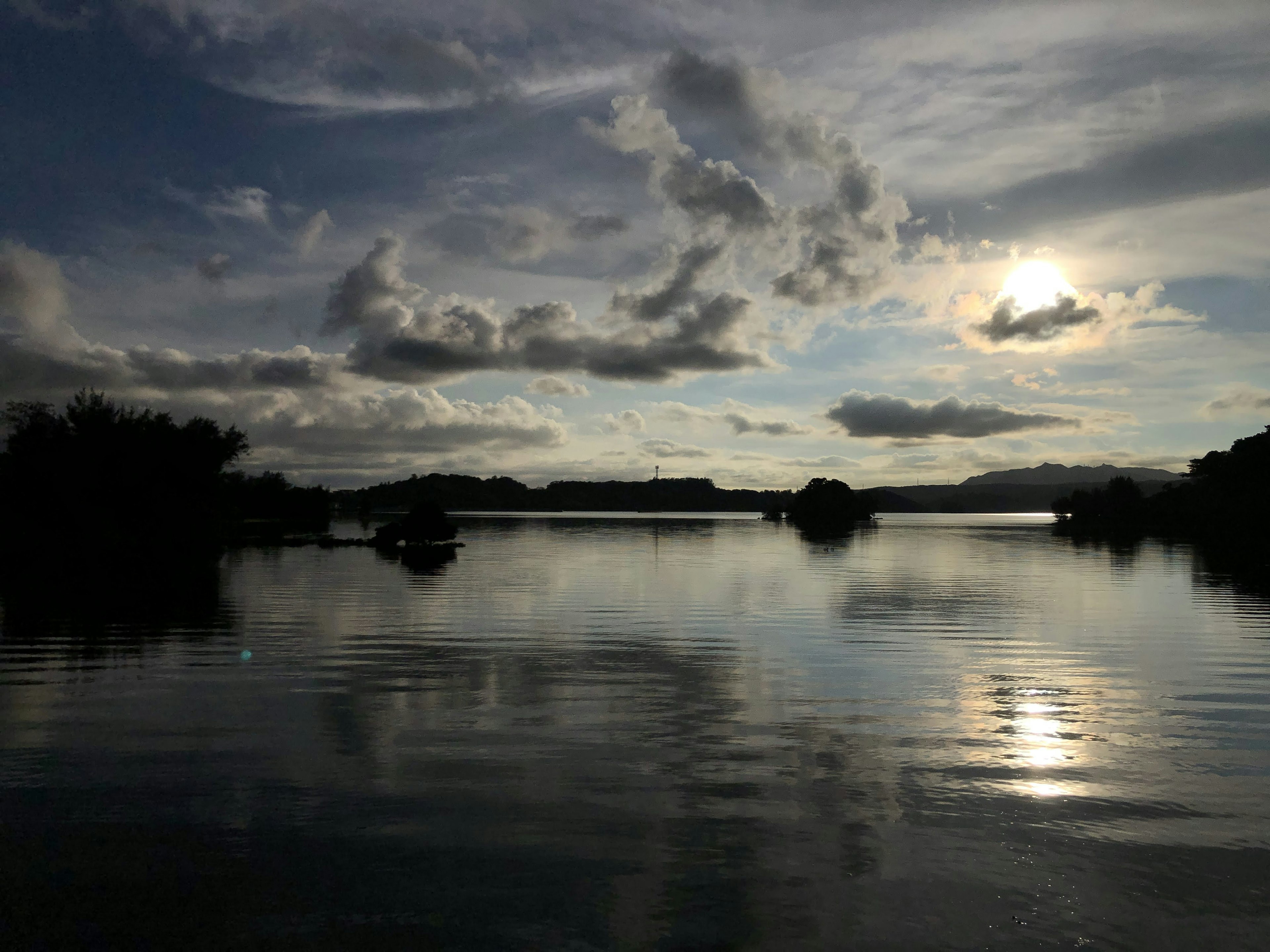 Danau tenang mencerminkan awan dan sinar matahari