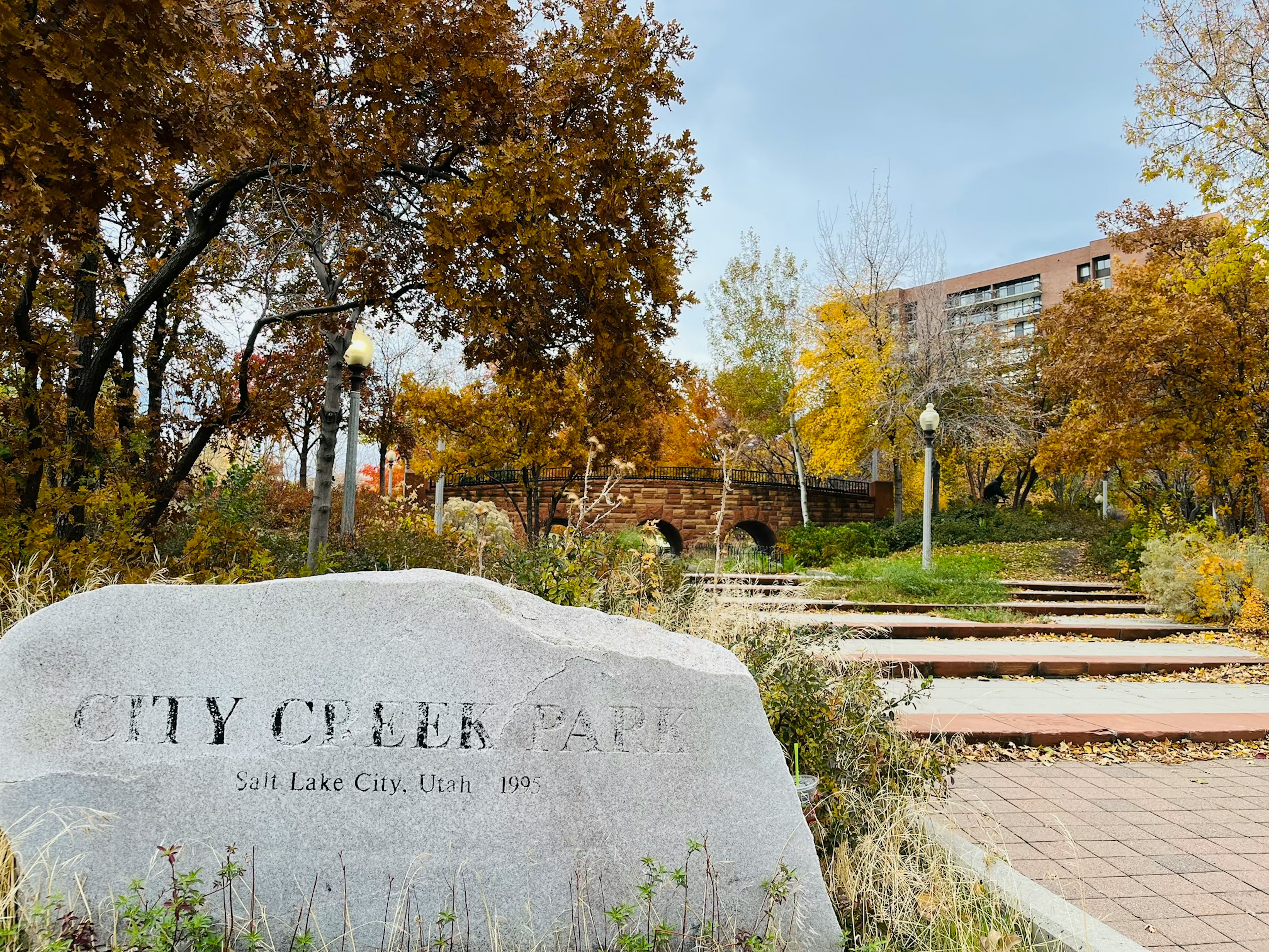 CITY CENTER라는 비문이 새겨진 돌 기념물과 가을의 나뭇잎과 산책로