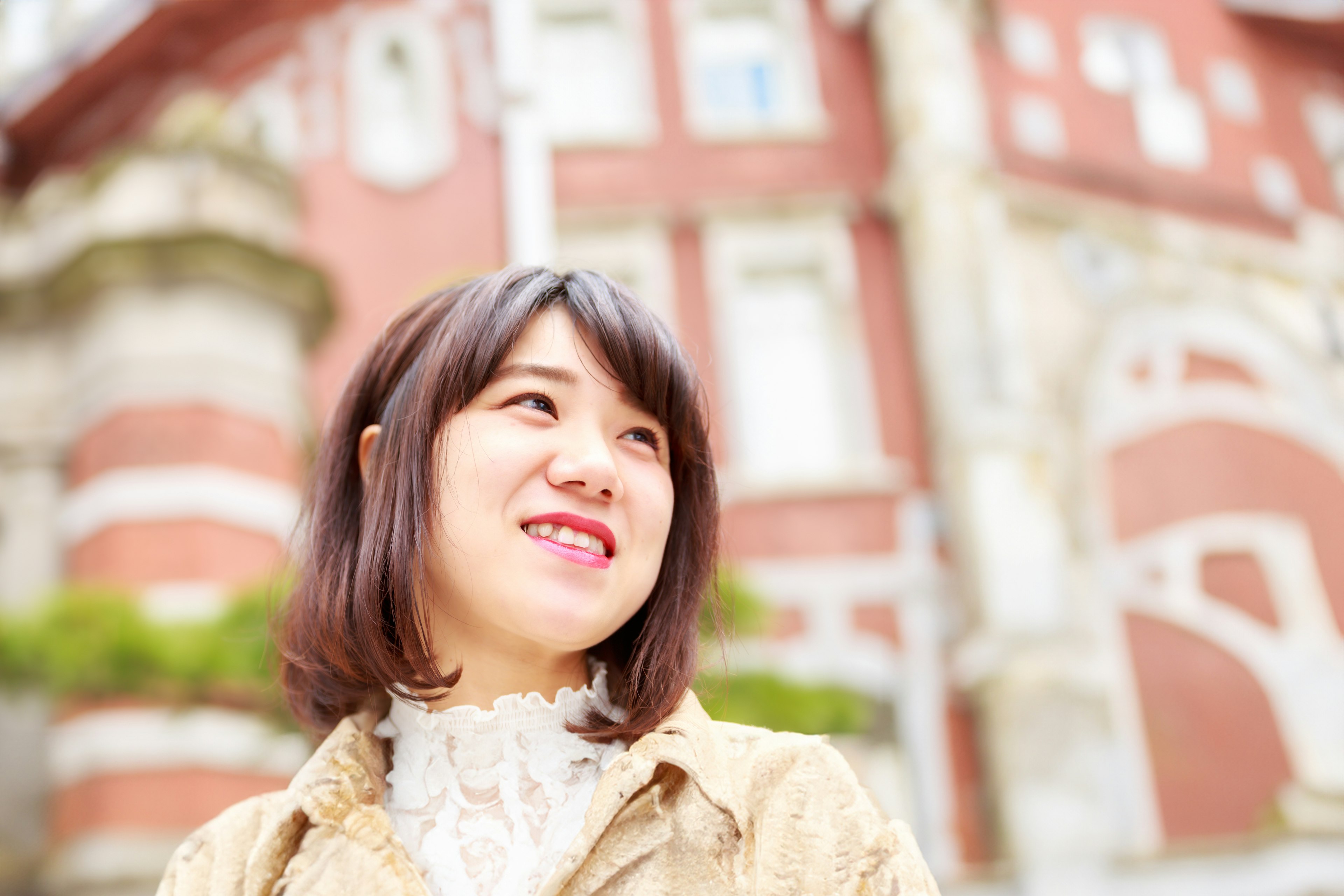 A smiling woman with shoulder-length hair in front of a red brick building