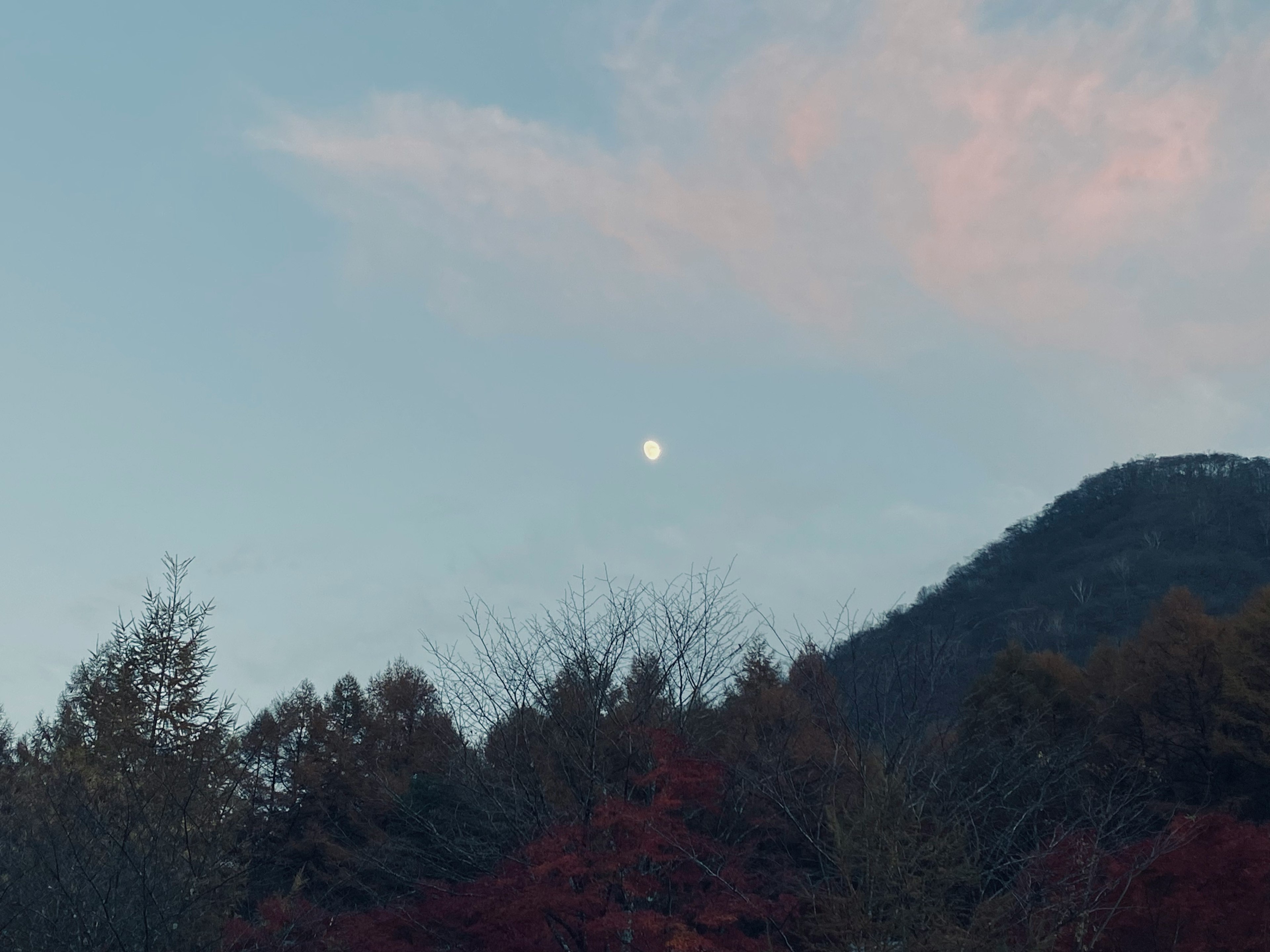 青空に浮かぶ月と山々の風景