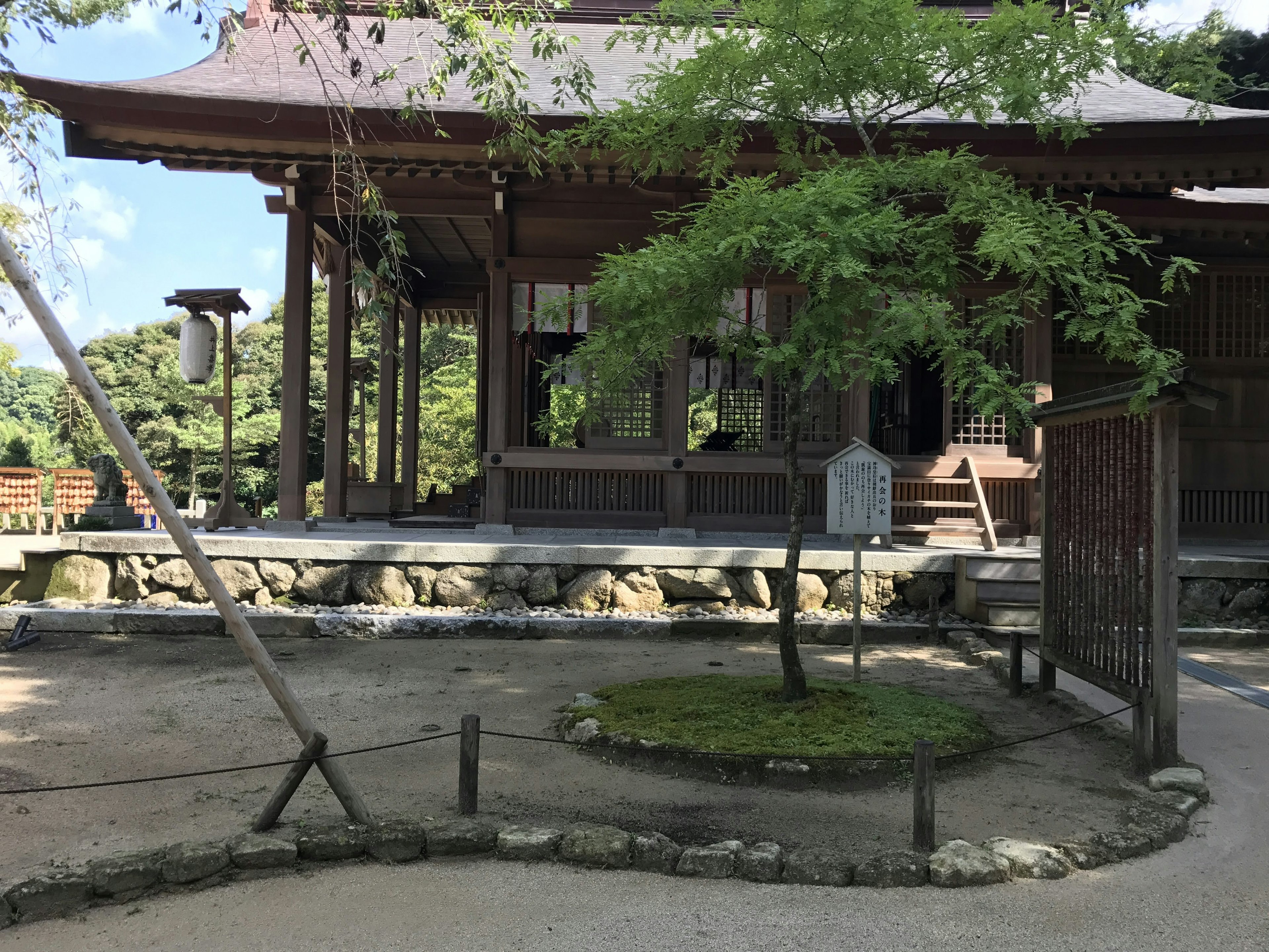 Traditionelles japanisches Tempelgebäude mit Garten und grünem Baum sowie Steinrand