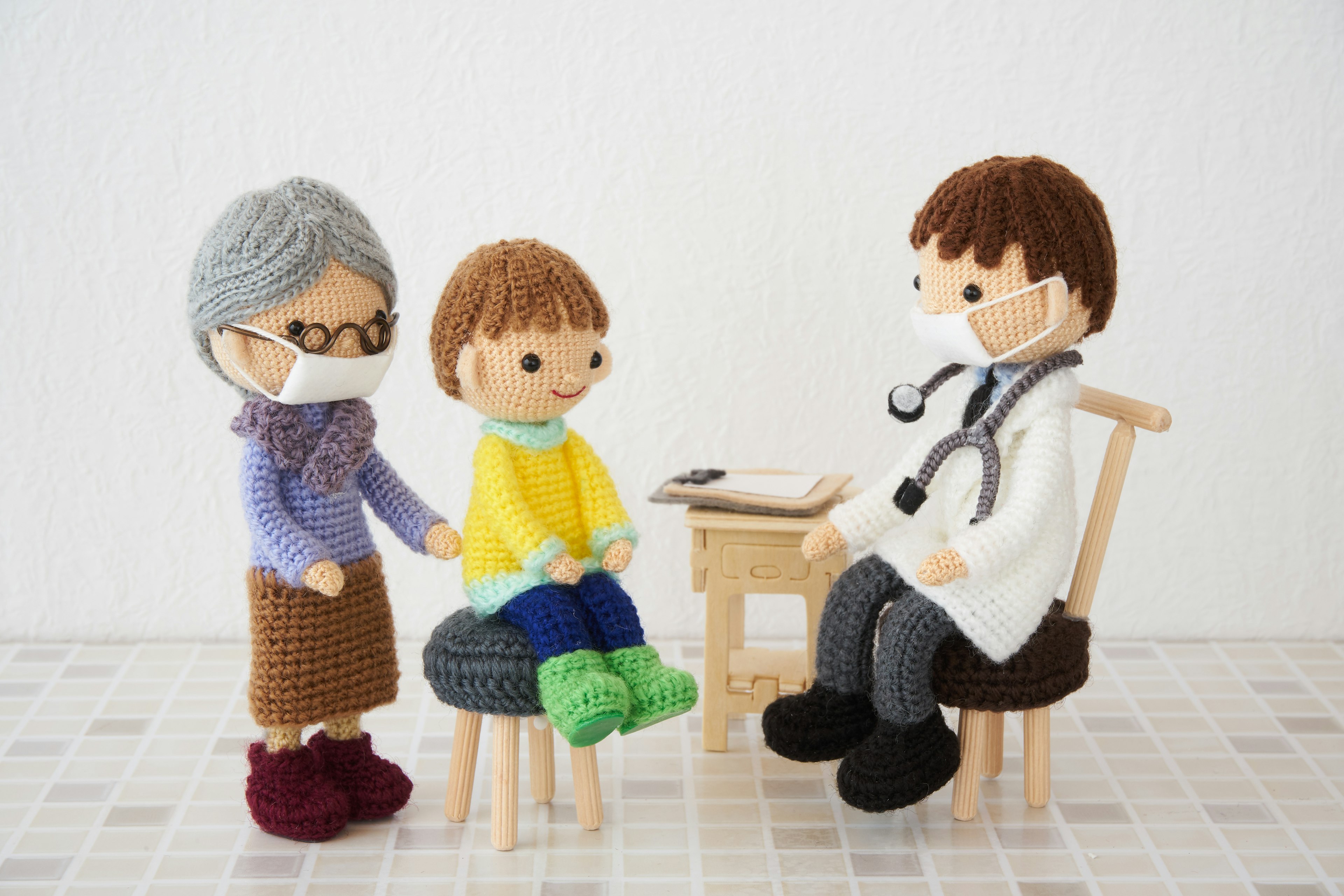 Knitted dolls of a doctor, child, and grandmother in a medical setting