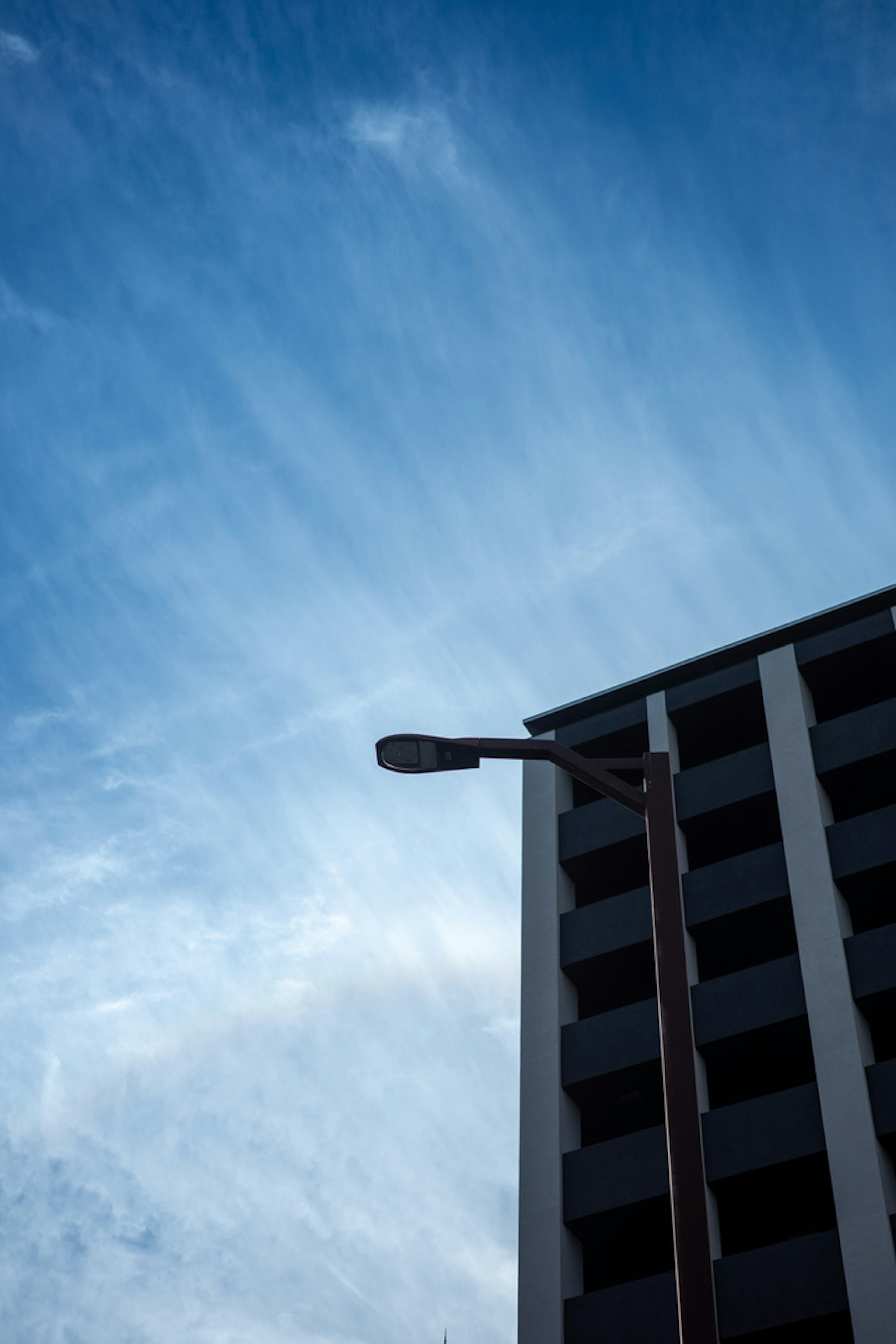 Building and streetlight under a blue sky with striped clouds