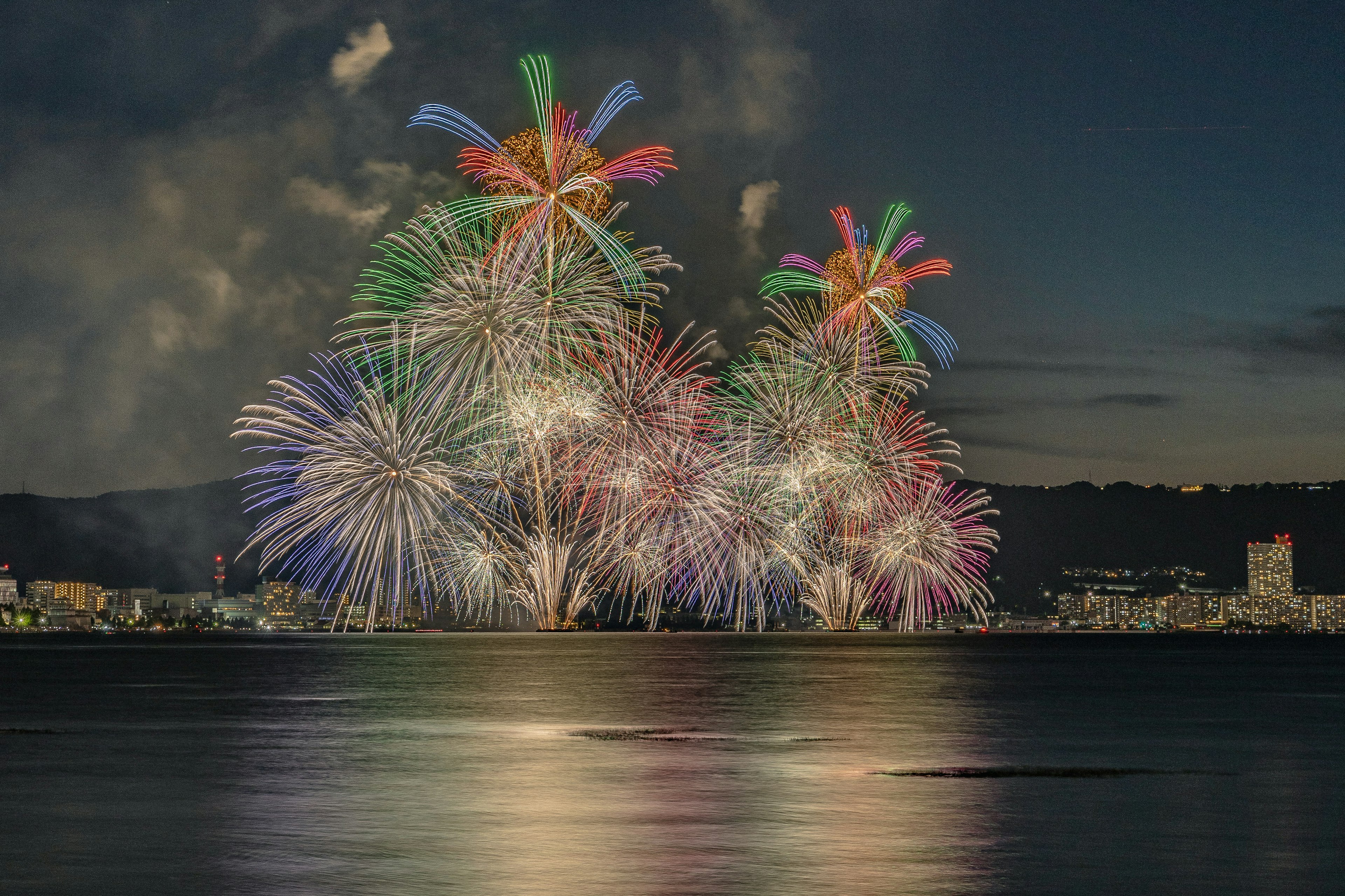 夜空に広がるカラフルな花火が水面に映る